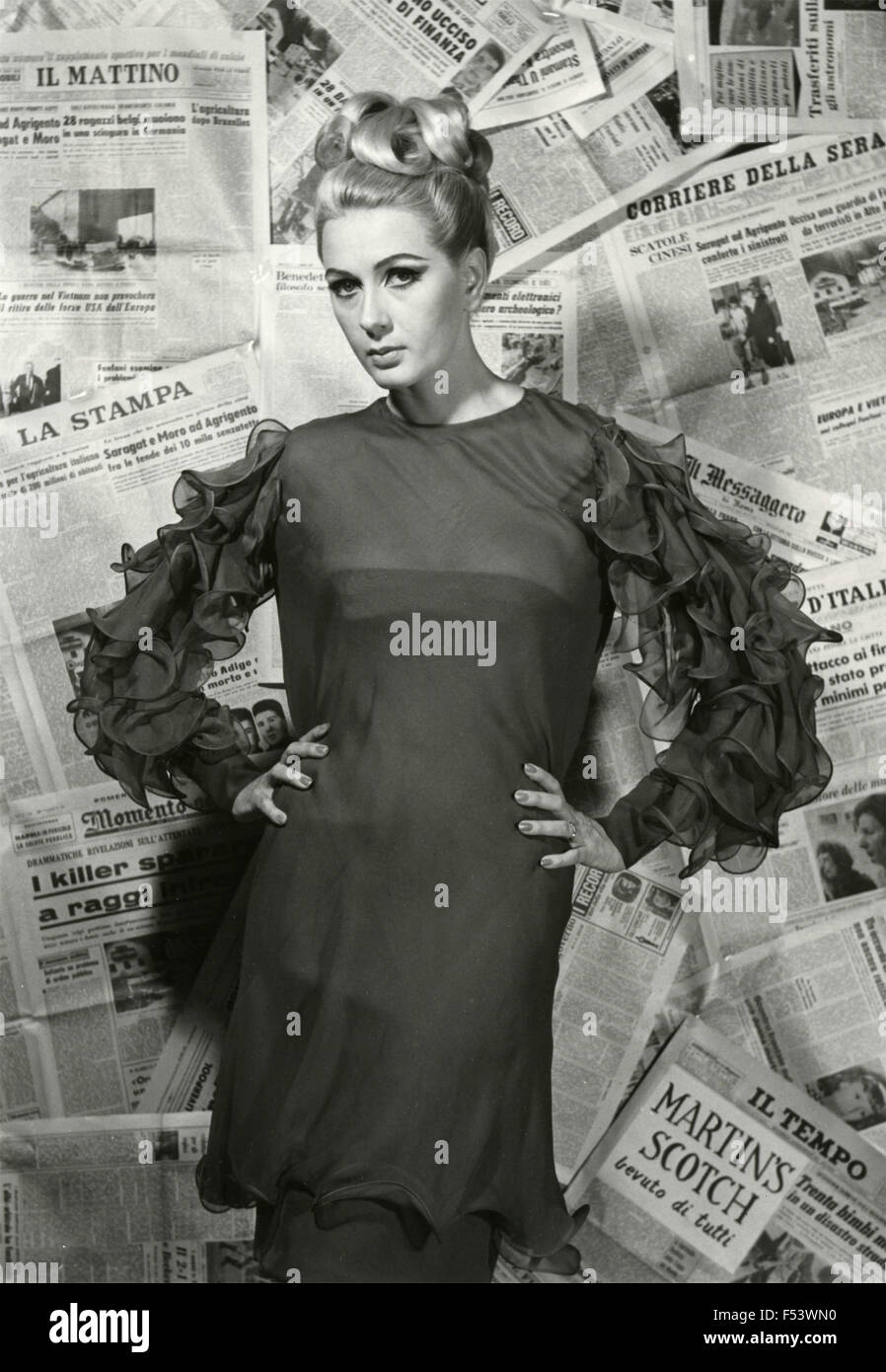 Ein Modell stellt eine Kleid auf einem Hintergrund von Zeitungen, Italien gemacht Stockfoto