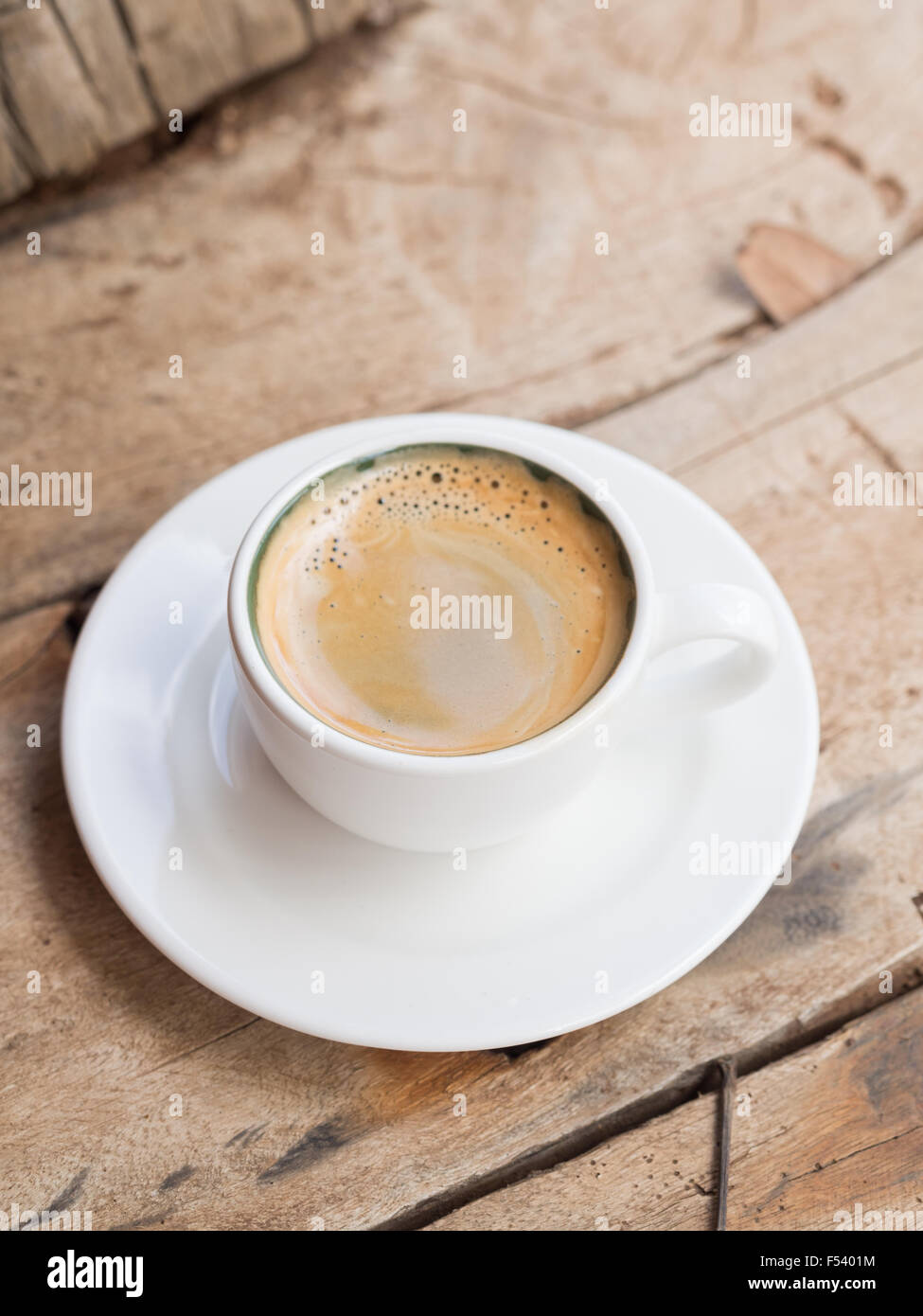 Doppelter Espresso in eine weiße Tasse über einem Dhau Holztisch gelegt. Erhöhten Blick, vertikale Ausrichtung. Stockfoto