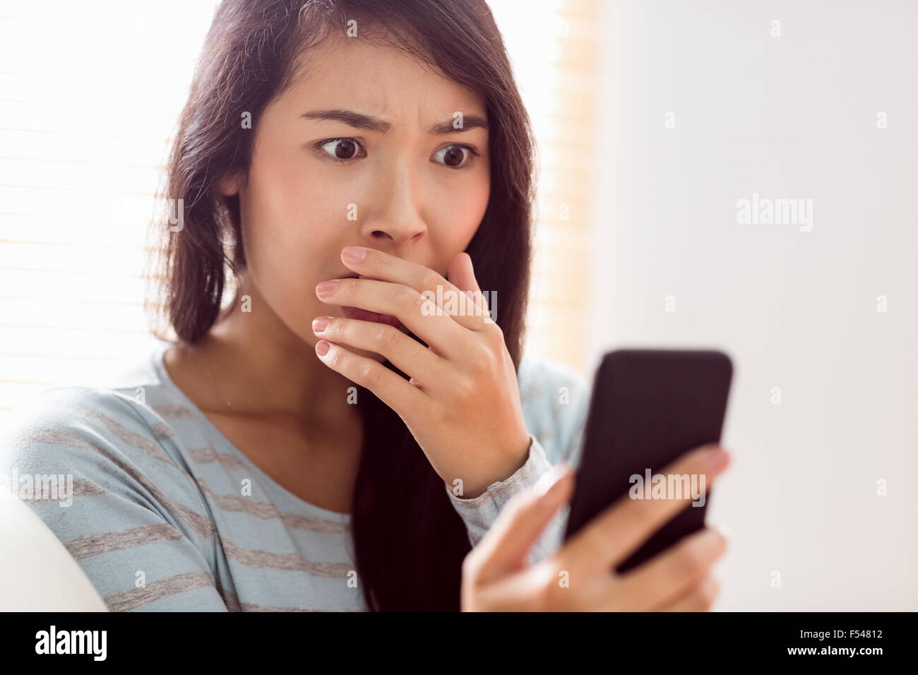 Asiatische Frau schockierenden Text zu lesen Stockfoto