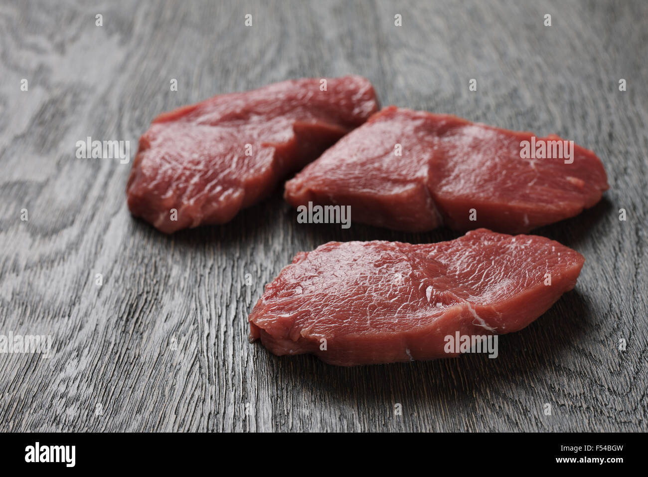 Rohes Rindfleisch Steaks auf einem dunklen Holzbrett Stockfoto