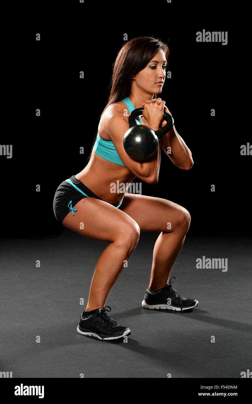 Junge Frau, die das Training mit Kettlebell auf dunklem Hintergrund Stockfoto