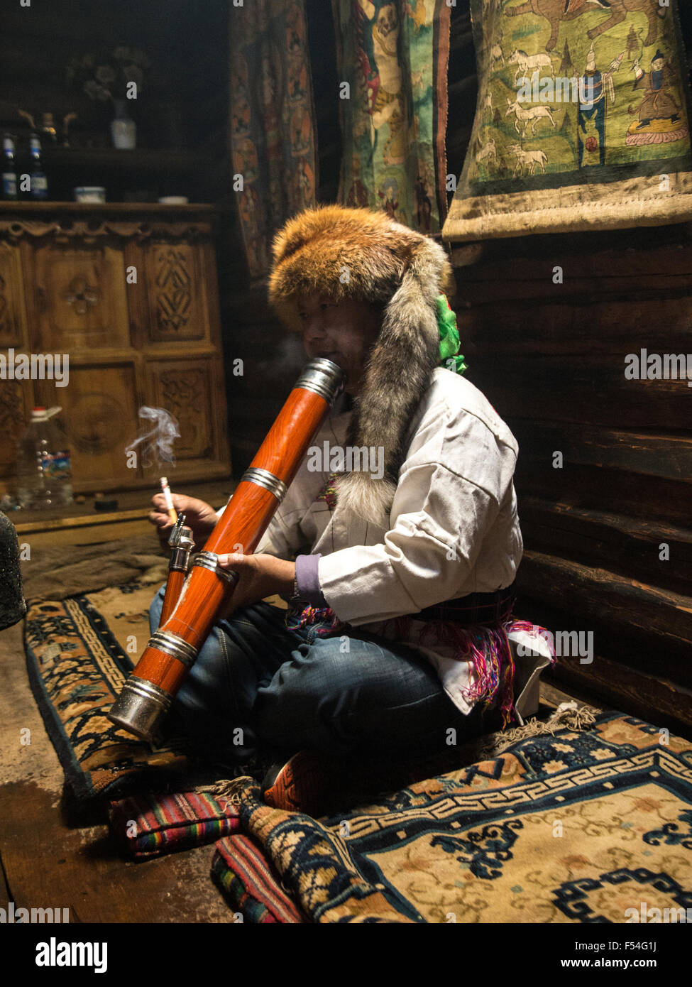 Portrait der Mann in traditioneller Kleidung der Halloween oder Naxi-Minderheit in China raucht eine Pfeife Stockfoto