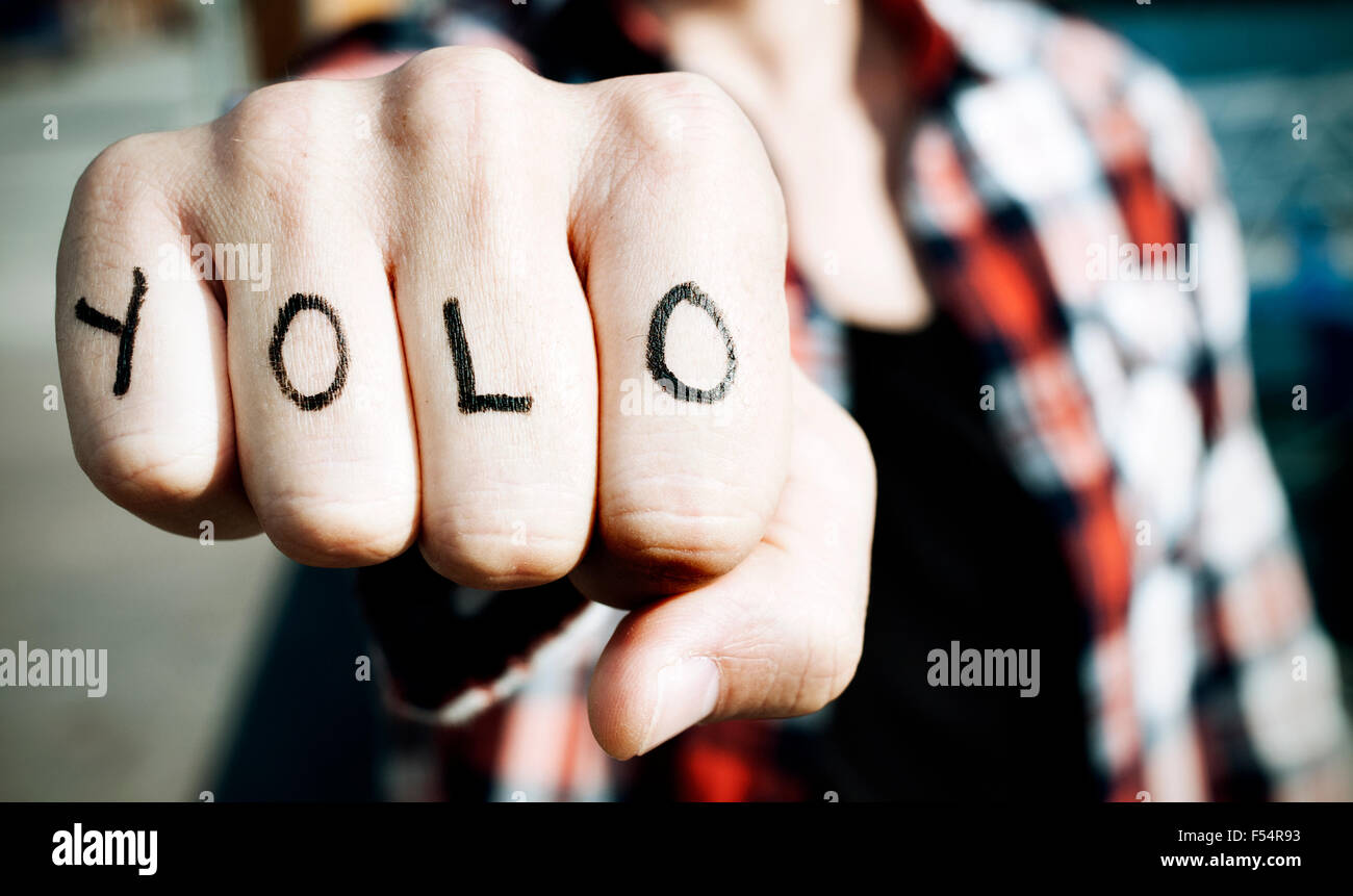 Nahaufnahme eines jungen Mannes mit dem Wort Yolo, für Sie leben nur einmal, in seine Knöchel mit einem Filtereffekt Stockfoto