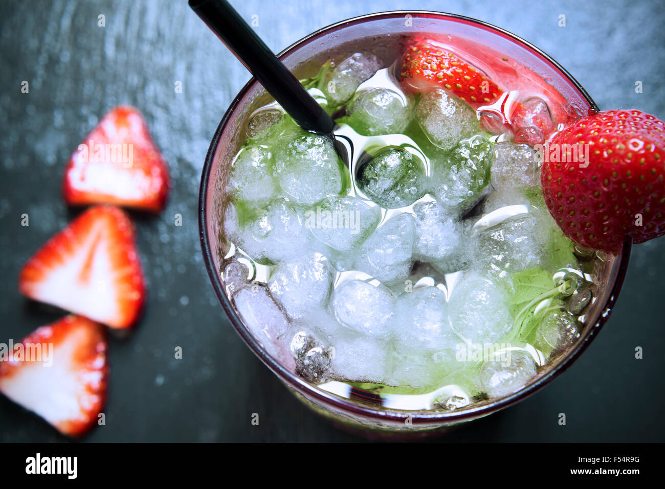 High-Angle Shot eines Glases mit einem Erdbeer Mojito, garniert mit einer Erdbeere auf schwarzem Schiefer Hintergrund Stockfoto
