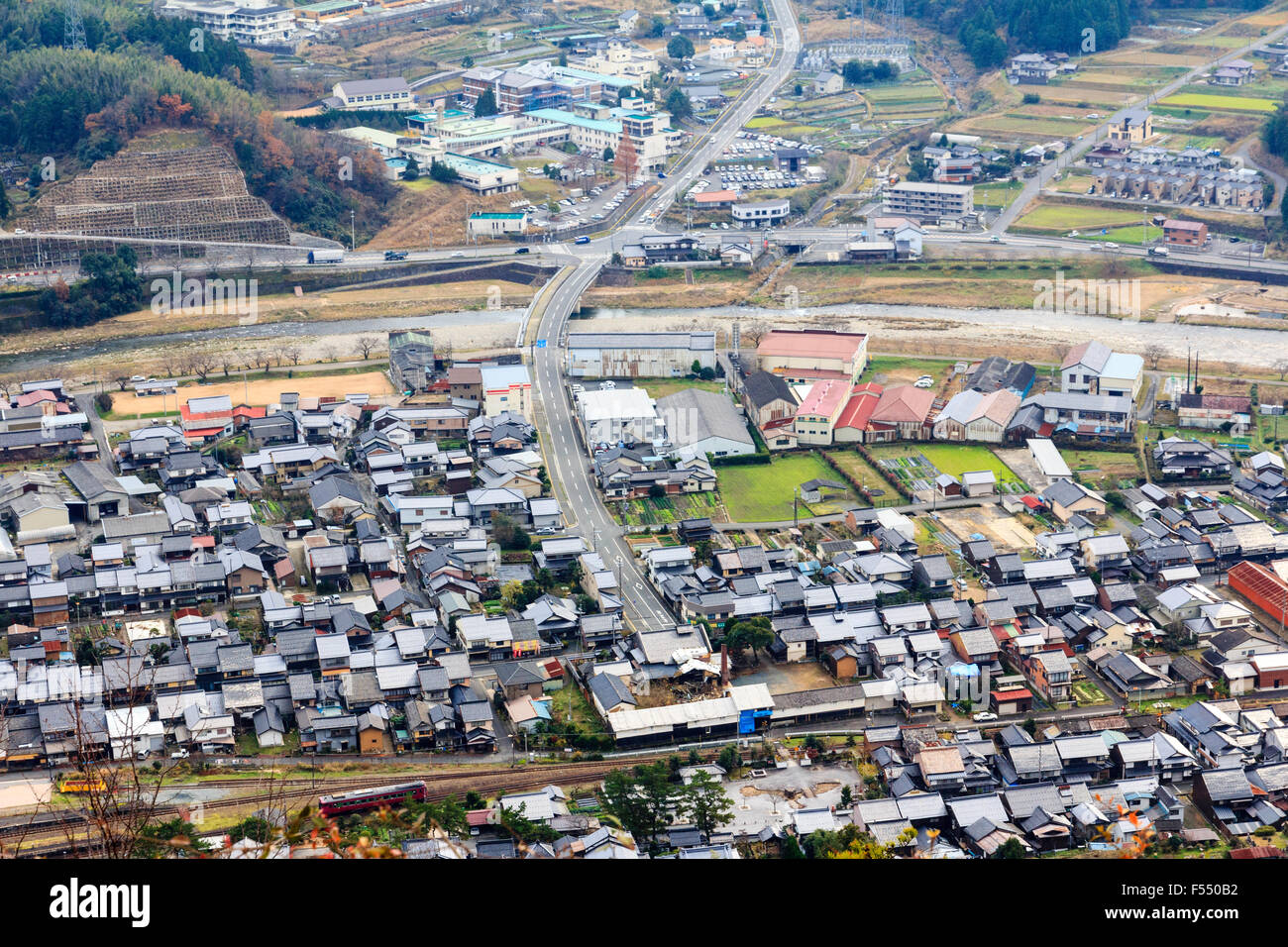 Japan, Takeda. Kleinen japanischen Stadt von Hill Top Schloss gesehen. Fluss, der durch die Stadt, Bahnlinien und Hauptstraße, der Schnellstraße. Luftaufnahme.. Stockfoto