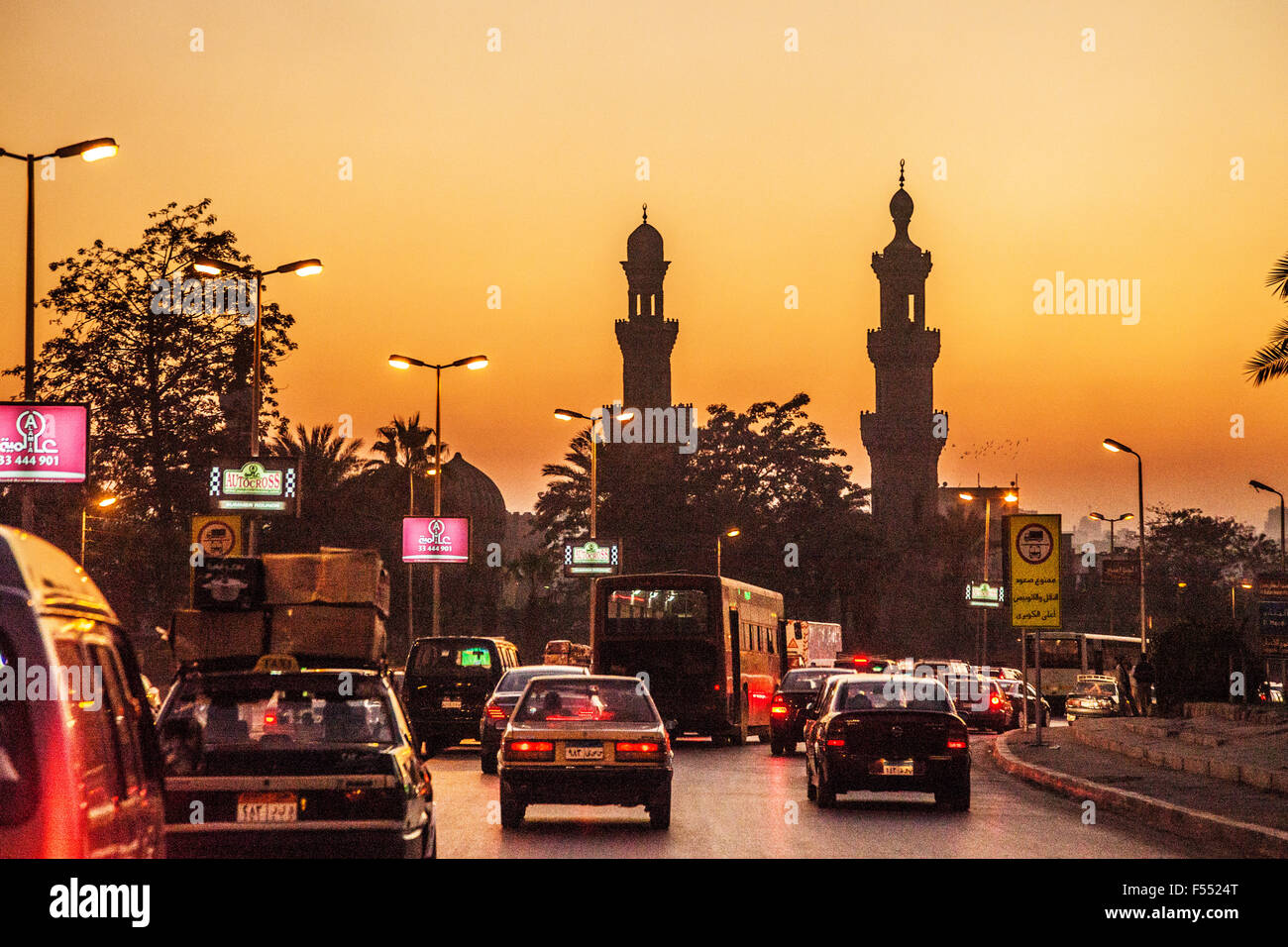 Cairo Traffic bei Sonnenuntergang mit zwei Minaretten Silhouette gegen einen goldenen Himmel. Stockfoto