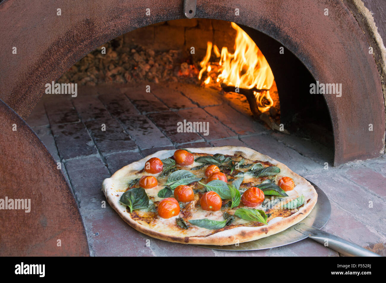 Frische Pizza auf Schale in traditionellen Ofen Stockfoto