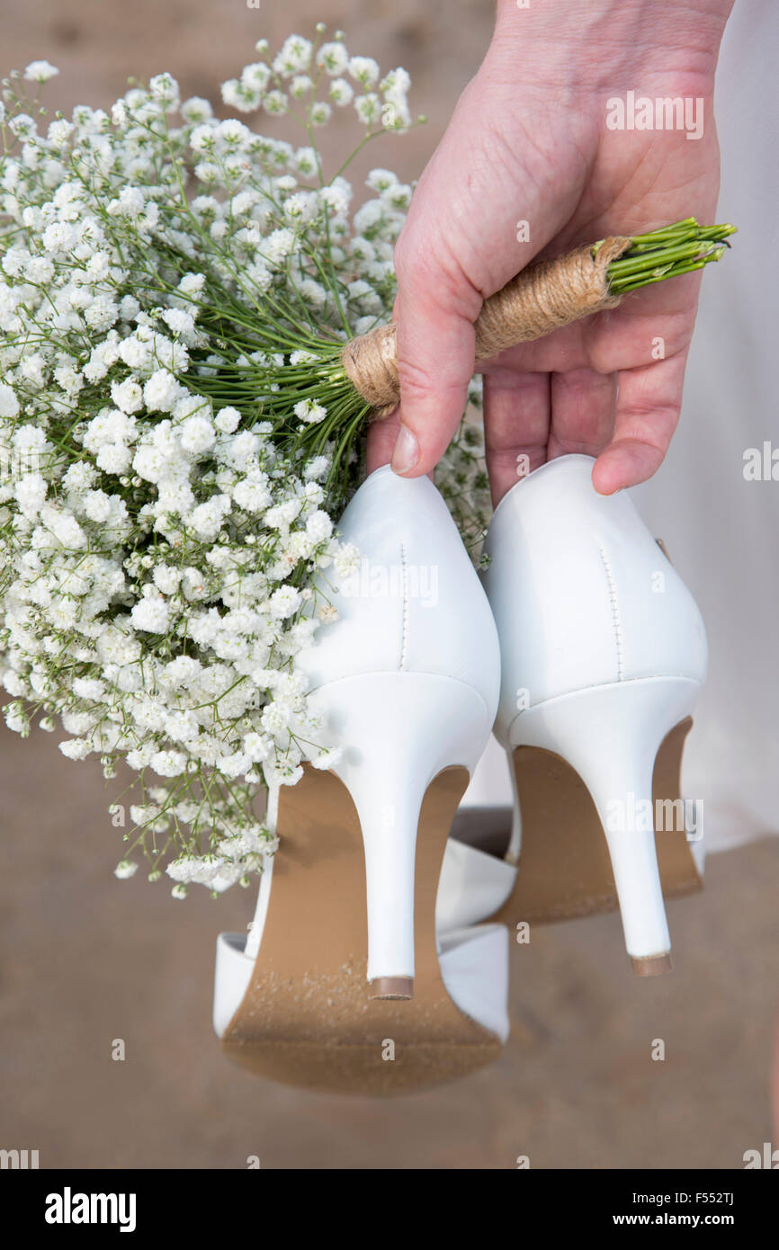 Bild der Braut hält high Heels und Blumen abgeschnitten Stockfoto