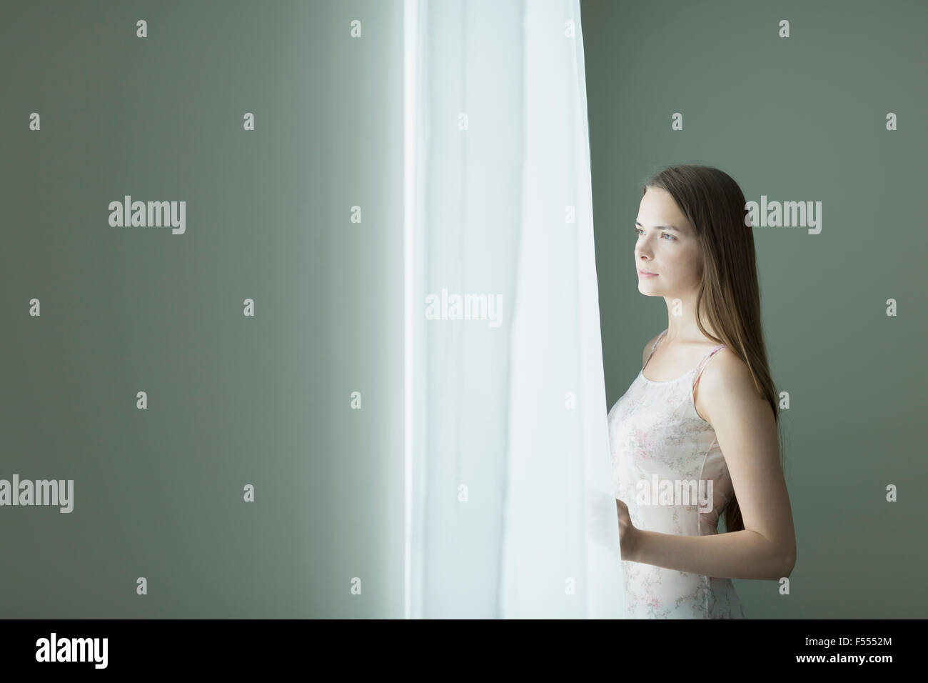 Nachdenkliche junge Frau Blick durch Fenster zu Hause Stockfoto