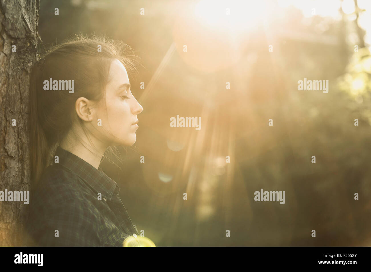 Seitenansicht der jungen Frau mit Augen geschlossen genießen Sonnenlicht im park Stockfoto