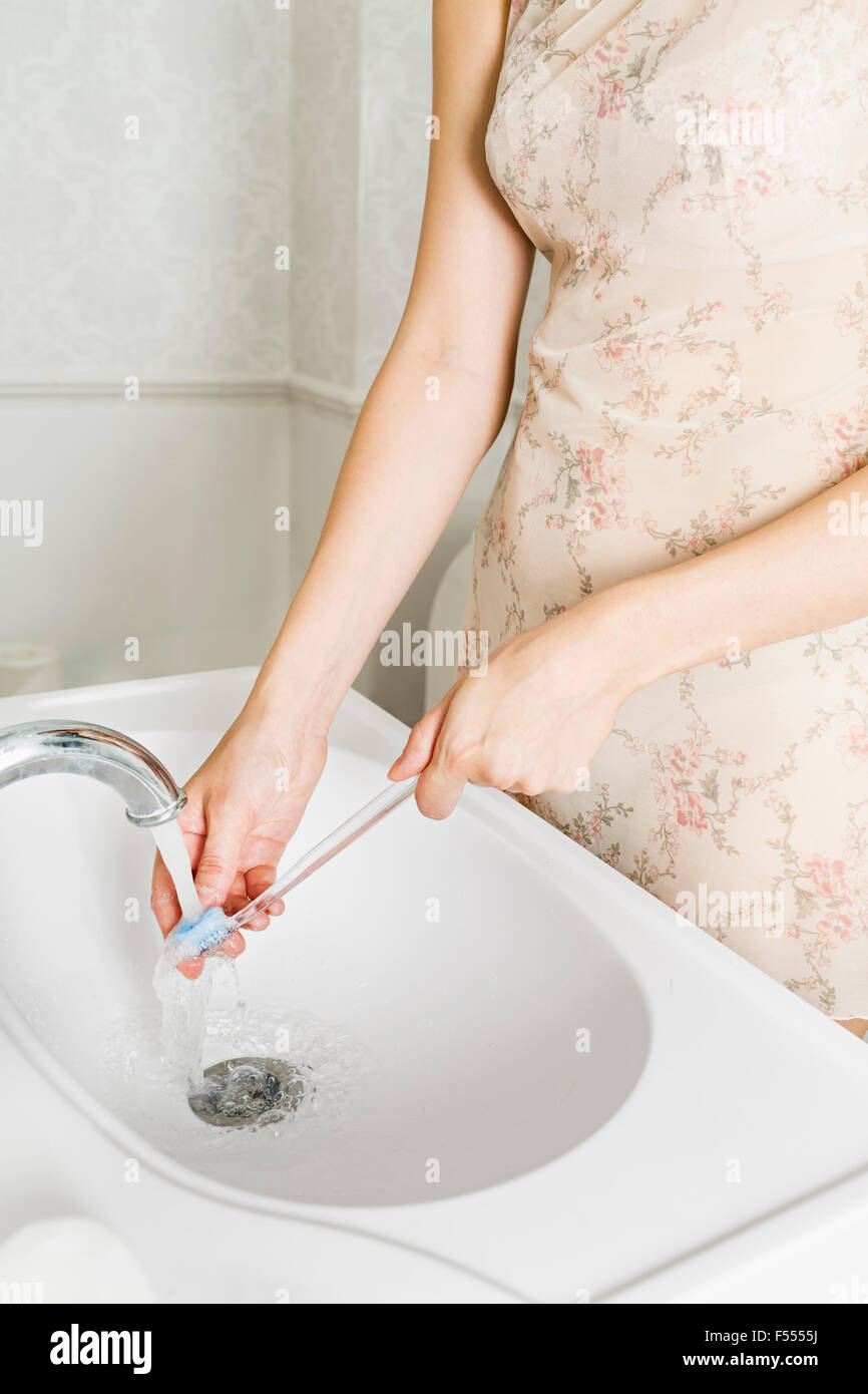 Mittelteil der Frau waschen Zahnbürste am Waschbecken im Bad Stockfoto