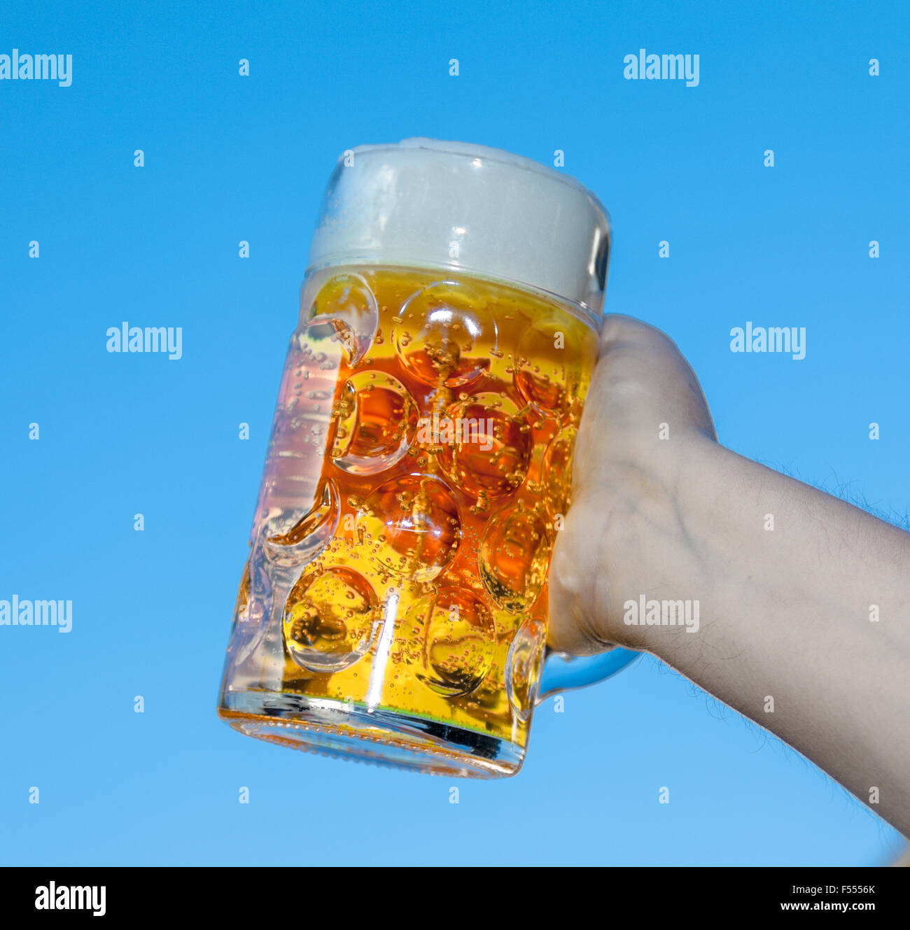 Hand mit Oktoberfest Bier vor blauem Hintergrund Stockfoto