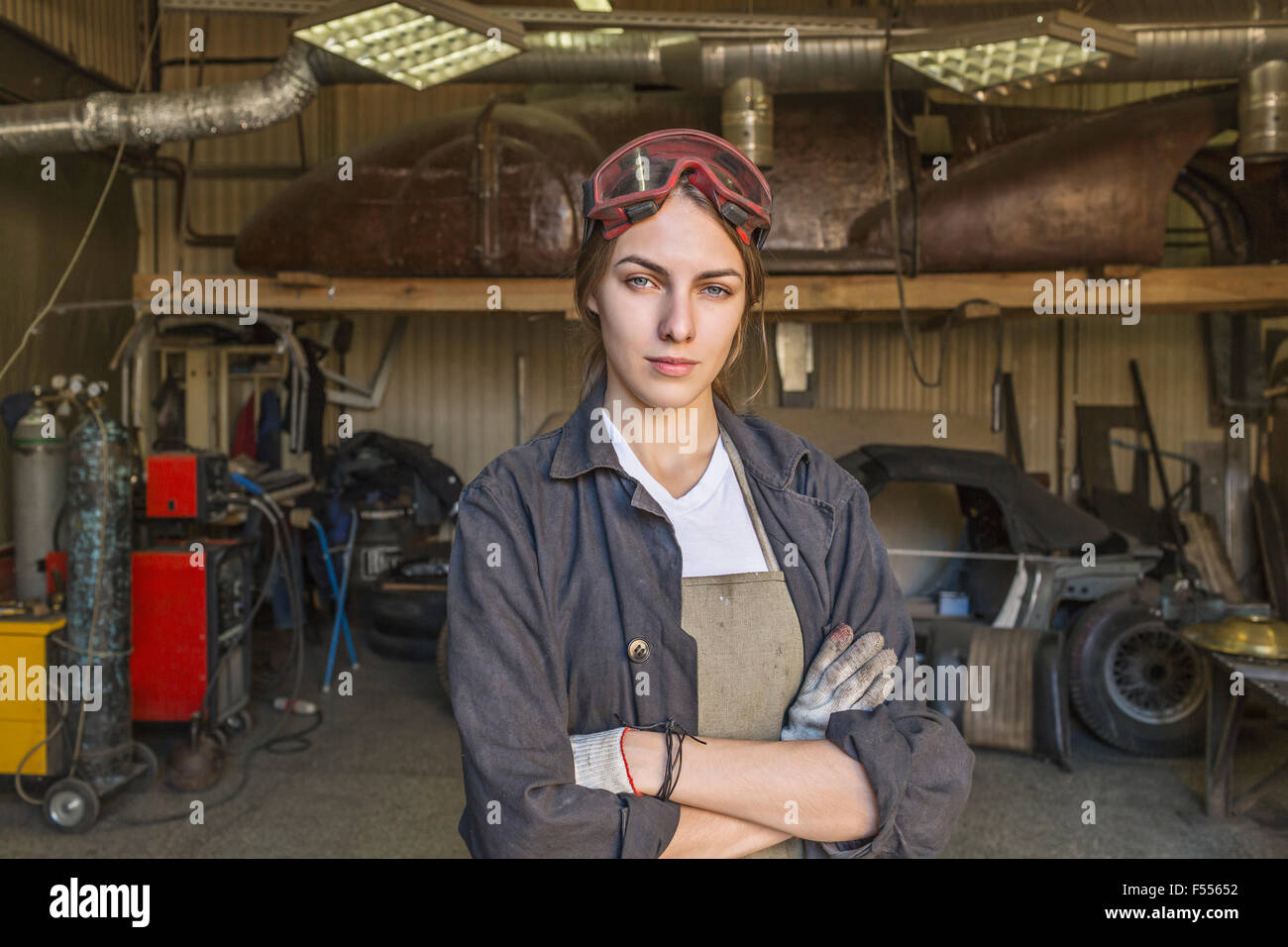 Porträt von zuversichtlich weibliche Mechaniker mit verschränkten in garage Stockfoto