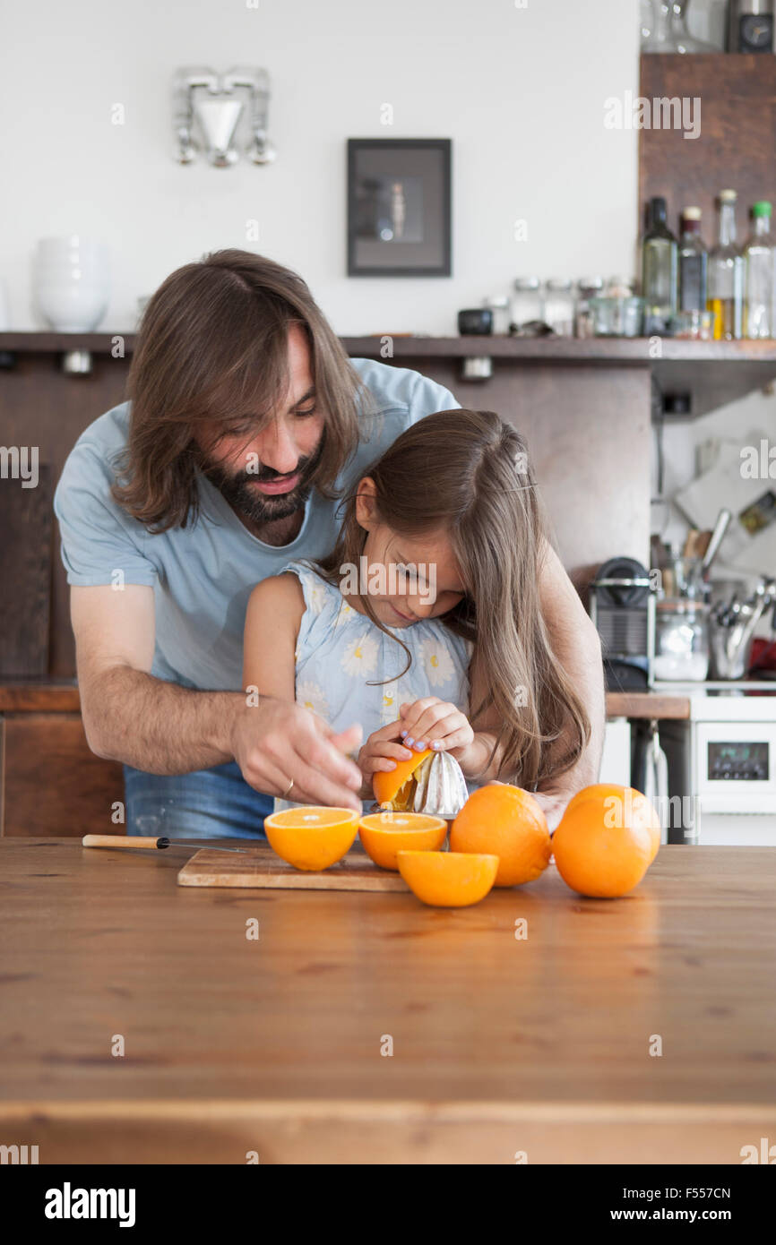 Vater, Tochter, Orangen aus Entsafter zu Hause auf Tisch Pressen zu unterstützen Stockfoto