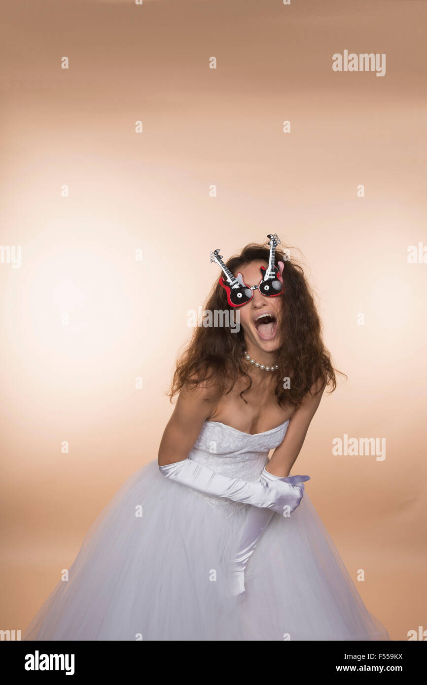 Aufgeregt Braut in Gitarre geformte Brille schreien vor farbigem Hintergrund Stockfoto