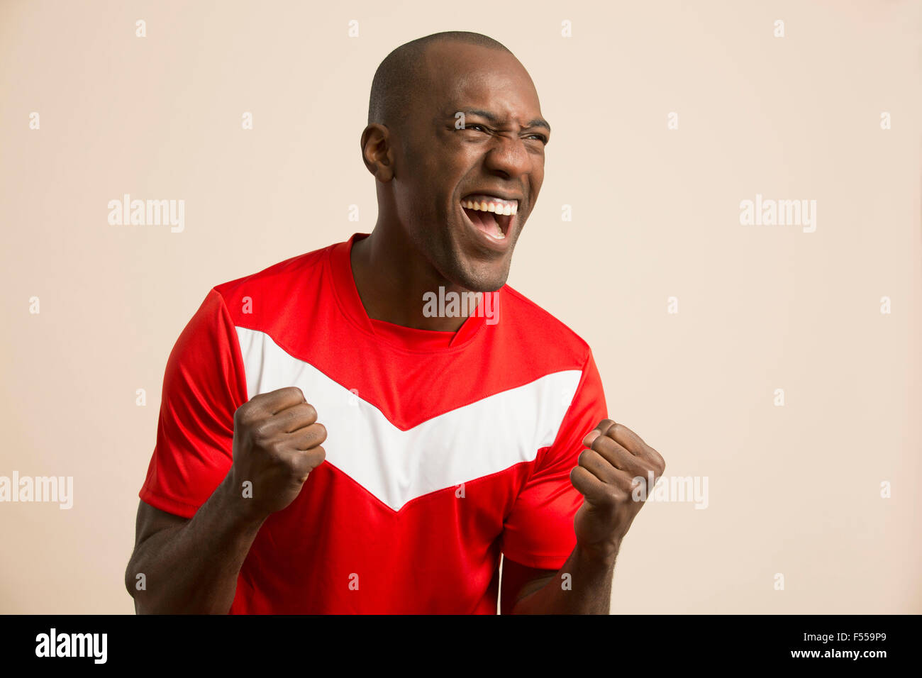 Aufgeregt Fußballer jubeln vor farbigem Hintergrund Stockfoto