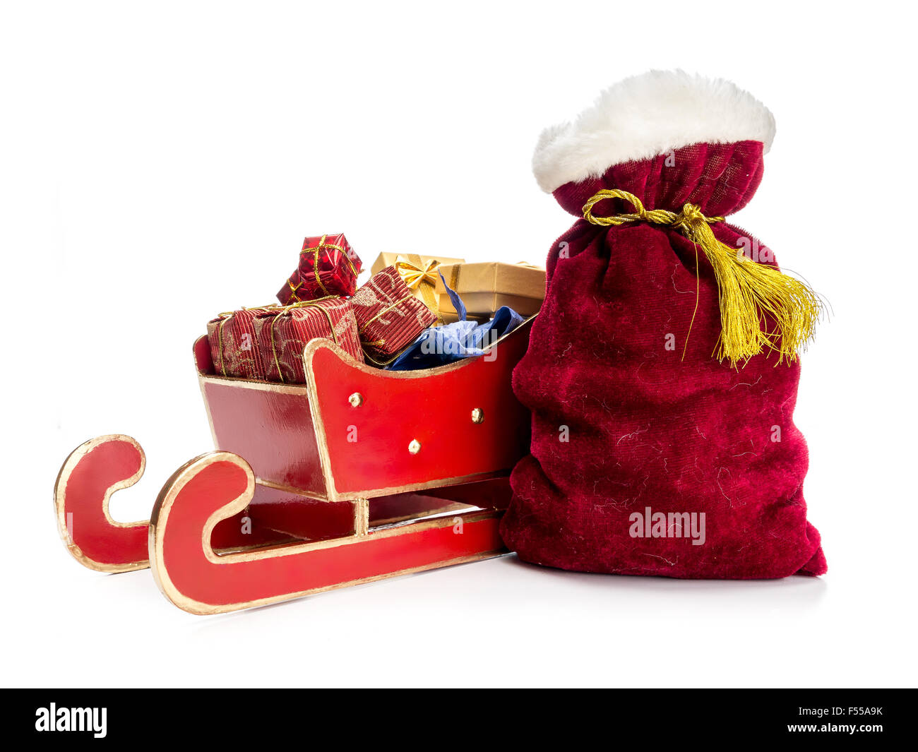 Roter Schlitten voller Weihnachtsgeschenke und Santa Claus Tasche auf weißem Hintergrund Stockfoto