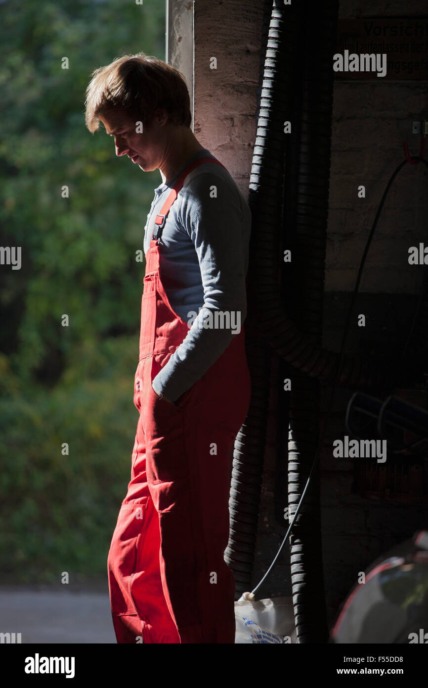 Seitenansicht der Mechaniker stehend mit Hand in der Tasche in der garage Stockfoto