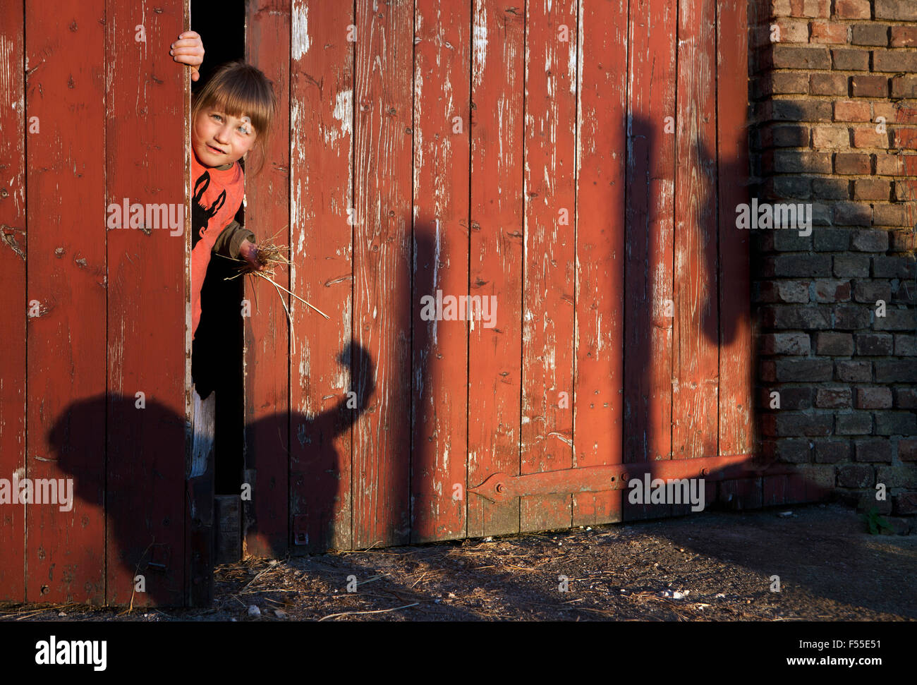 Porträt eines Mädchens spähen durch Scheunentor Stockfoto