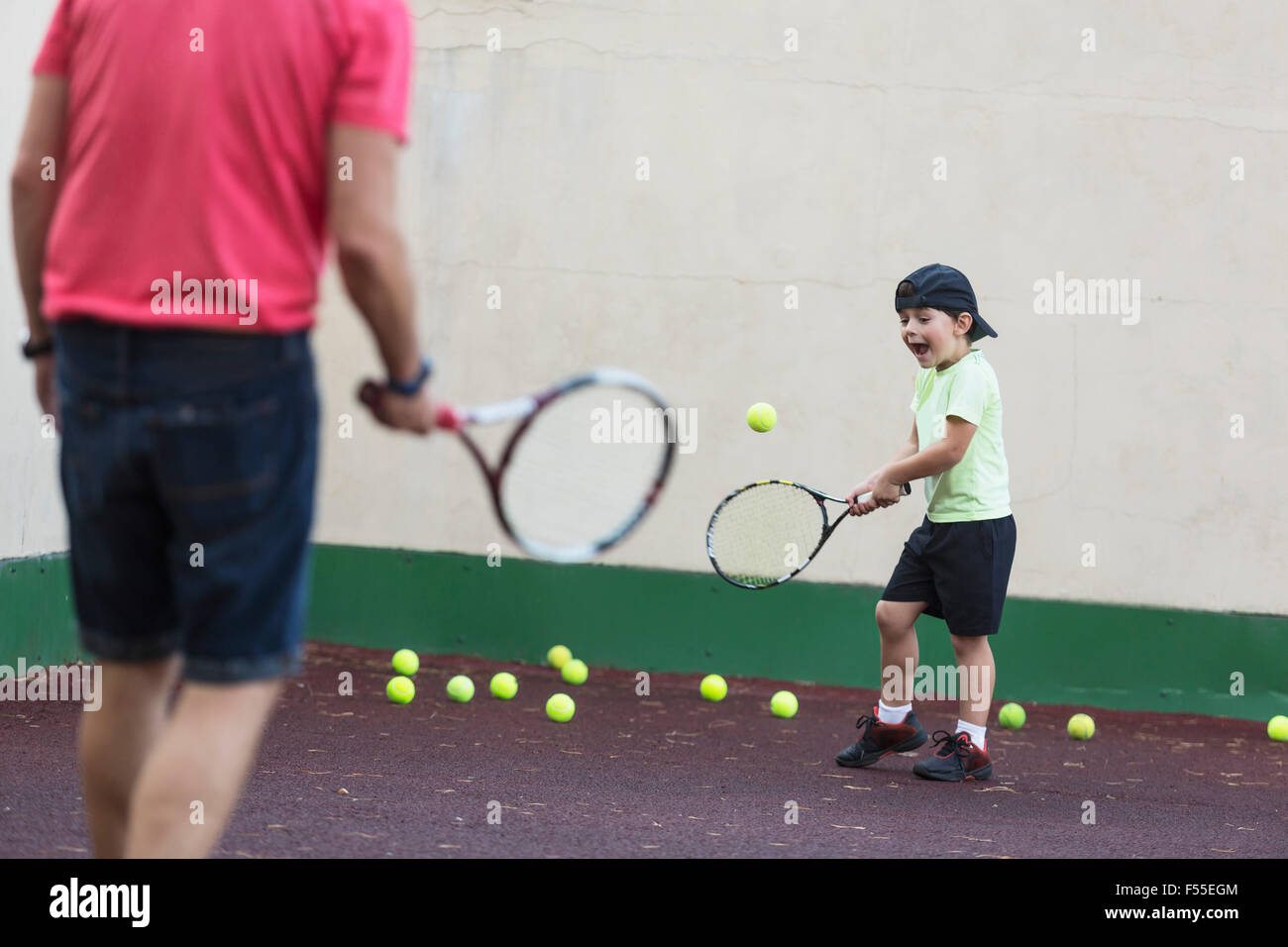 Vater und Sohn spielen Tennis auf Feld Stockfoto
