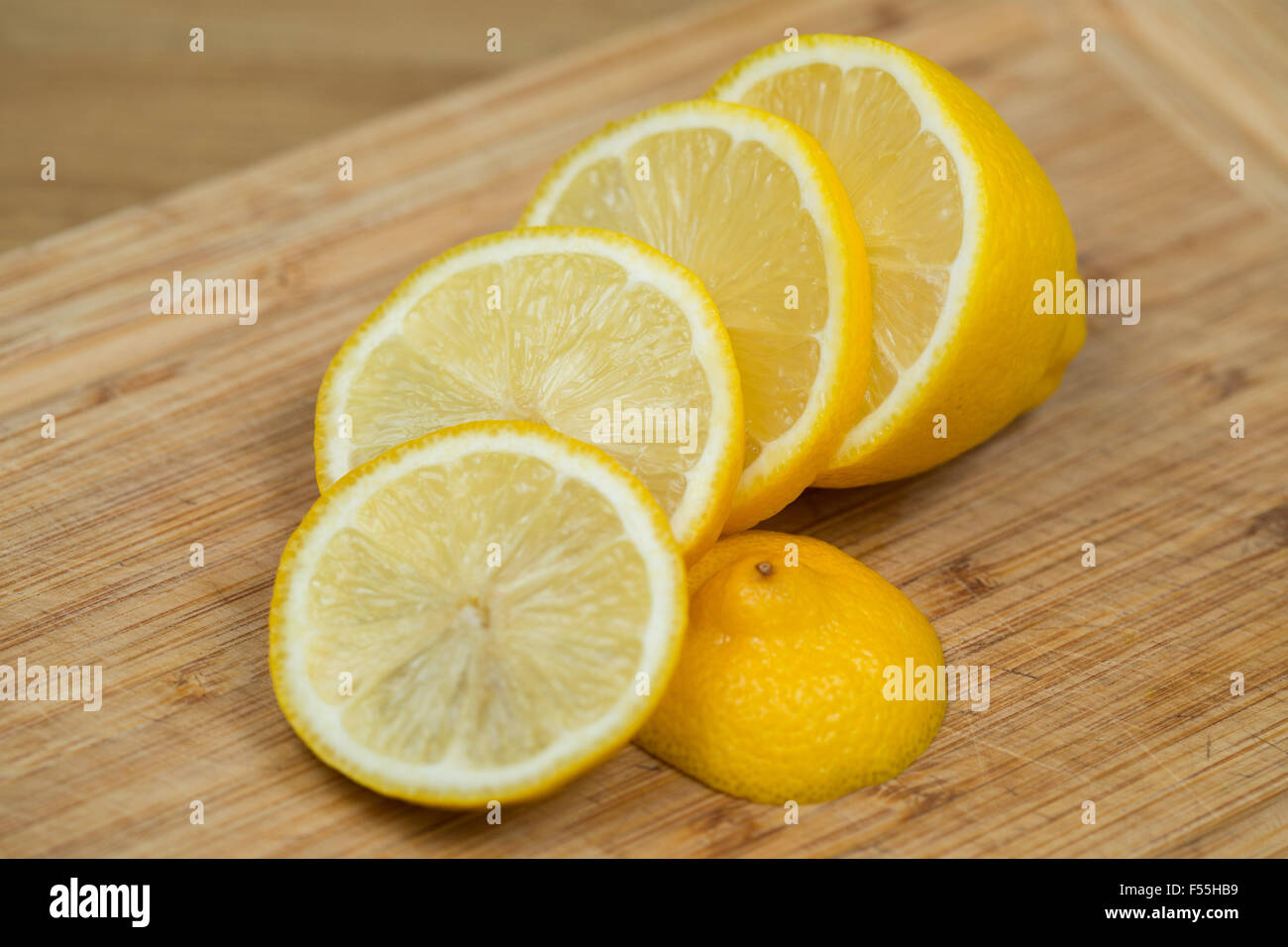 Eine frische Zitrone in Scheiben geschnitten auf ein Schneidbrett aus Holz. Stockfoto