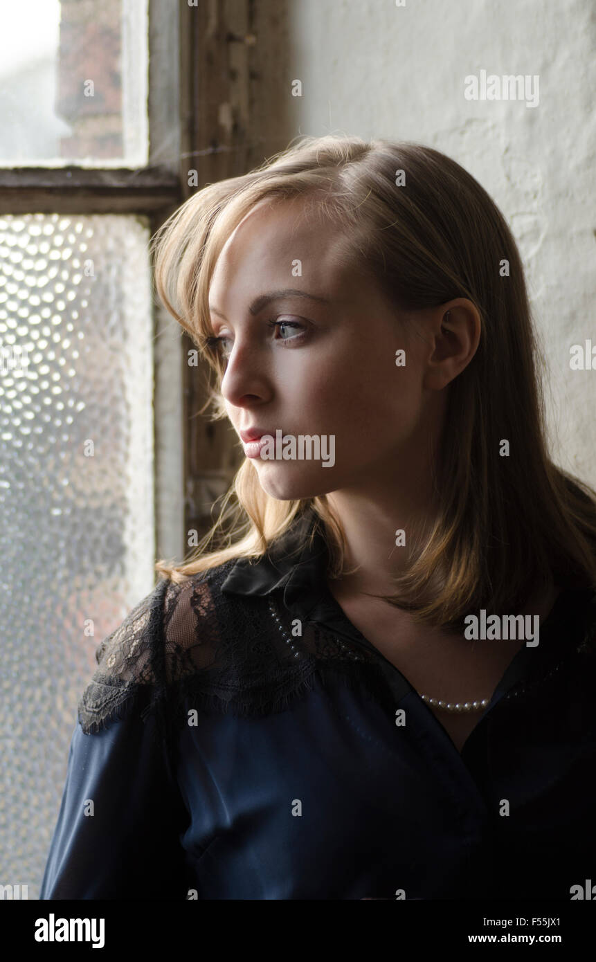 Schöne junge Frau aus dem Fenster Stockfoto
