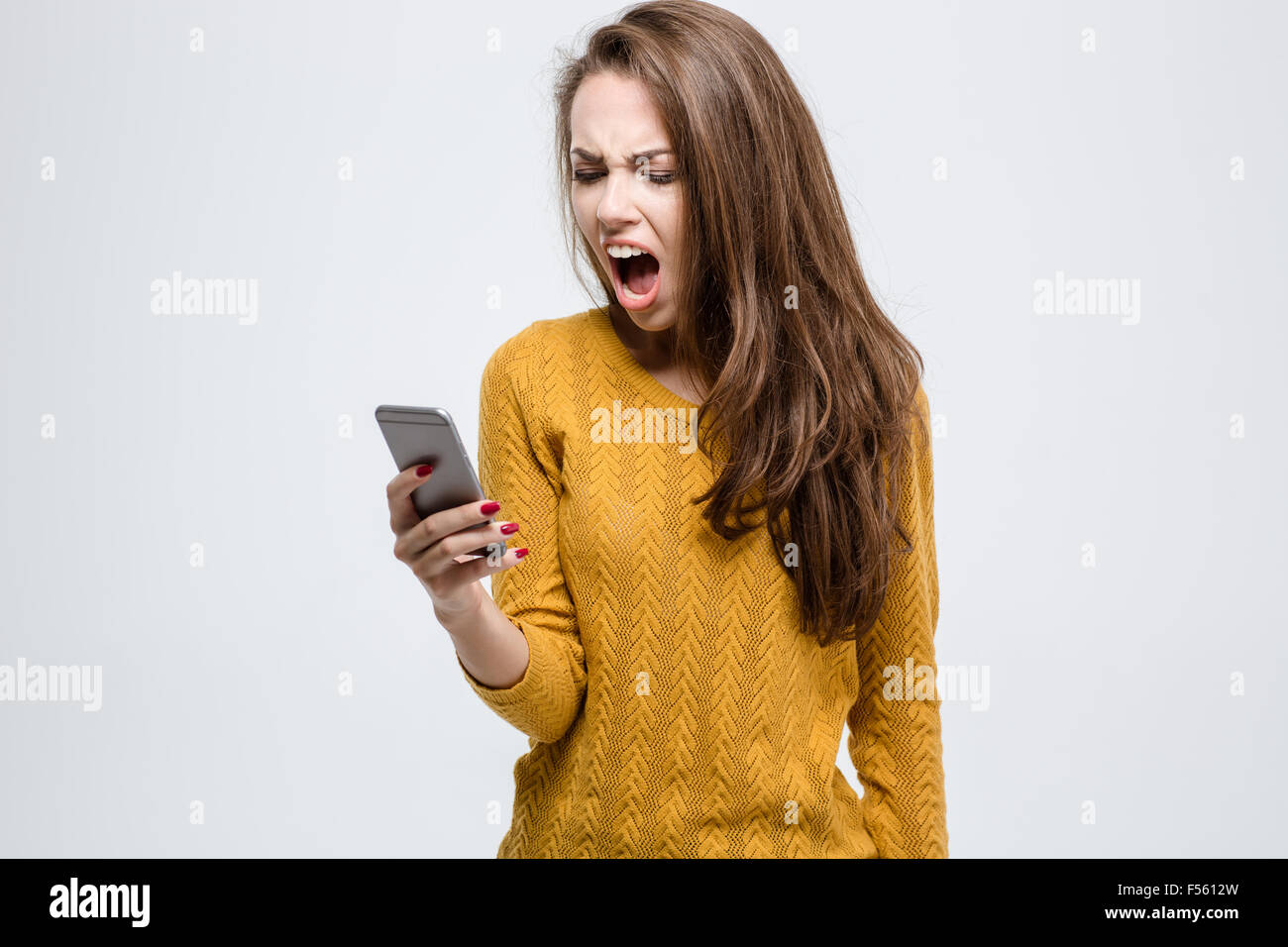 Porträt von Wut junge Frau schreiend auf Smartphone isoliert auf weißem Hintergrund Stockfoto