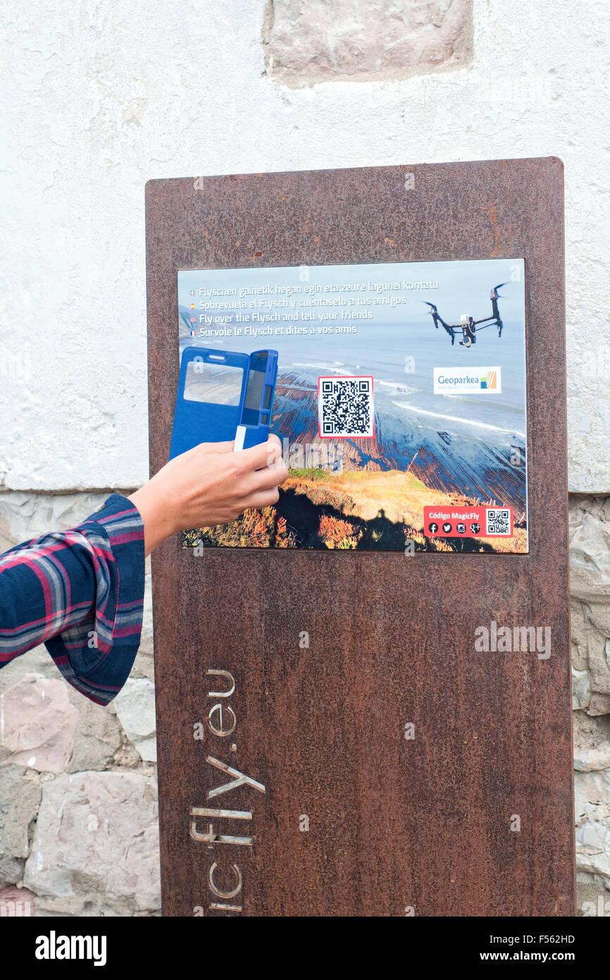 Person, die einen QR-Code mit einem Smartphone in eine Informationstafel über den Geopark auf Zumaia liest. Gipuzkoa. Baskisches Land. Stockfoto
