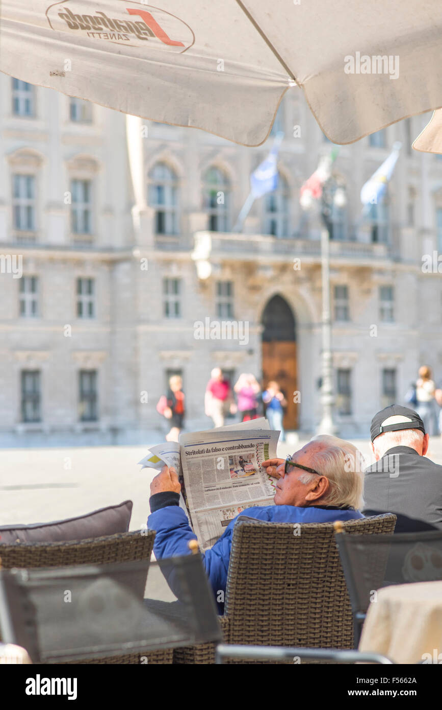 Italien, Café, Bar, ein Tourist liest eine Zeitung an einem Tisch vor einem Café in Triest. Stockfoto