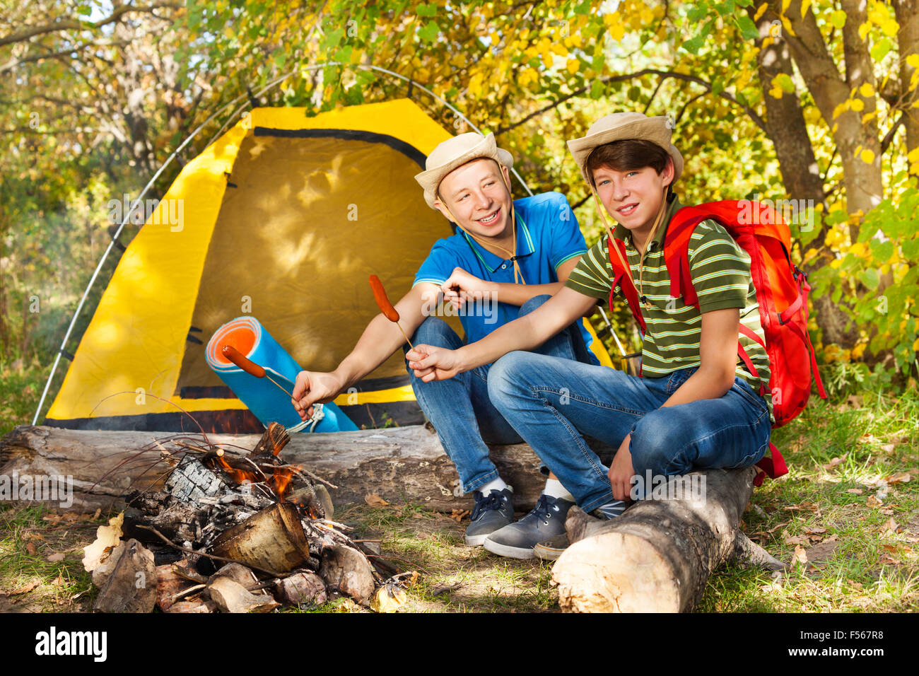 Teenie jungen sitzen auf Campingplatz mit Würstchen-sticks Stockfoto