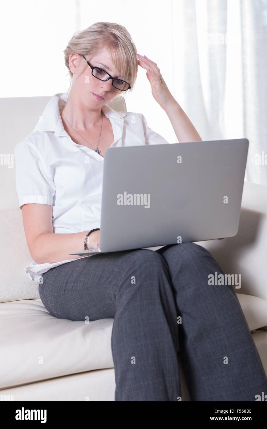 junge attraktive Frau mit Laptop auf couch Stockfoto