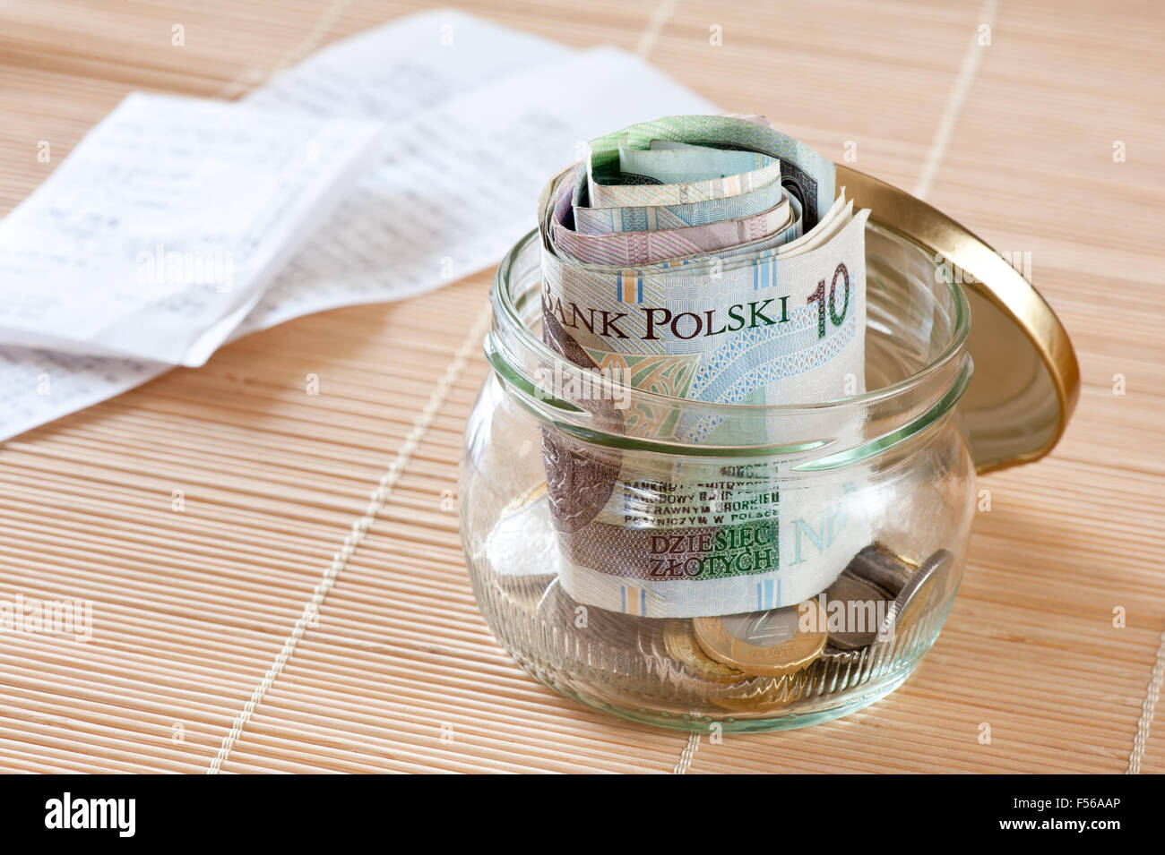 Geld sparen und Quittungen, polnische Zloty furled Banknoten Haufen und Münzen sammeln aus transparentem Glas jar stehen... Stockfoto