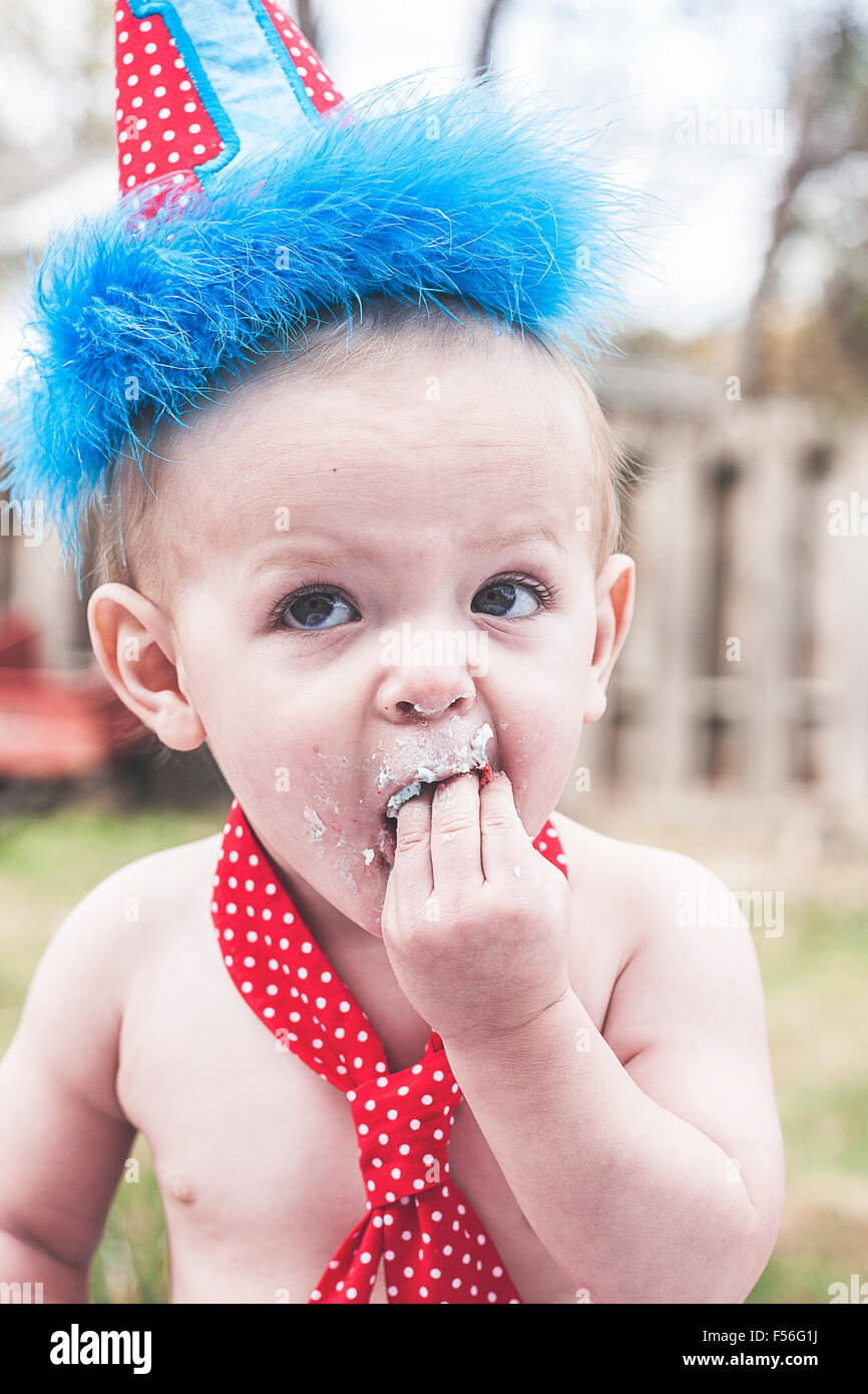 Baby Boy mit Hand und Mund zu ersten Geburtstag Kuchen Stockfoto