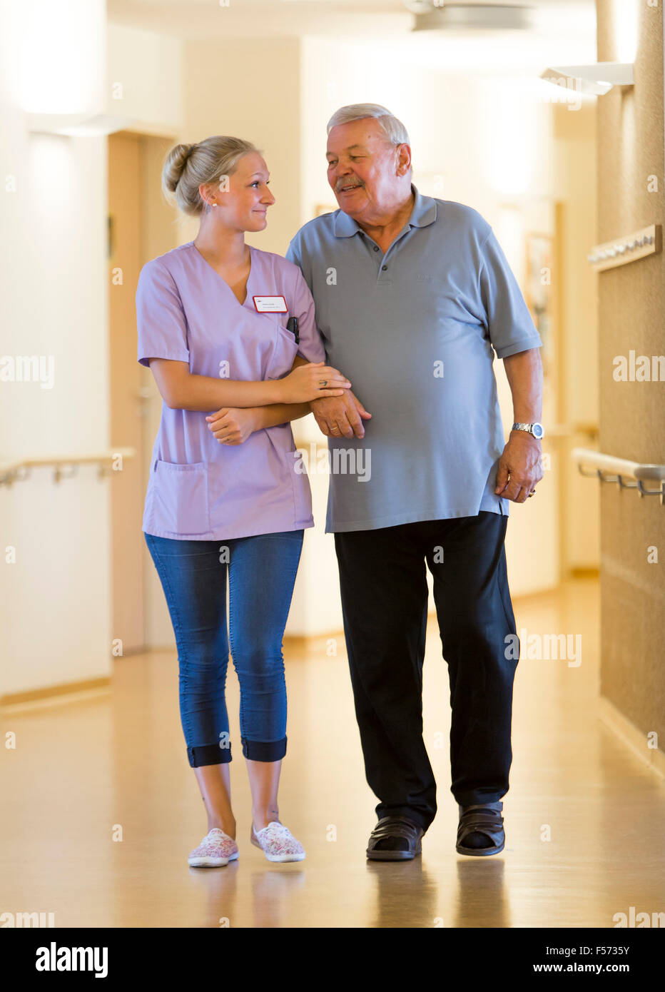 Altenpflege in einem Pflegeheim, Krankenschwester hilft einen älteren Mann zu Fuß Stockfoto