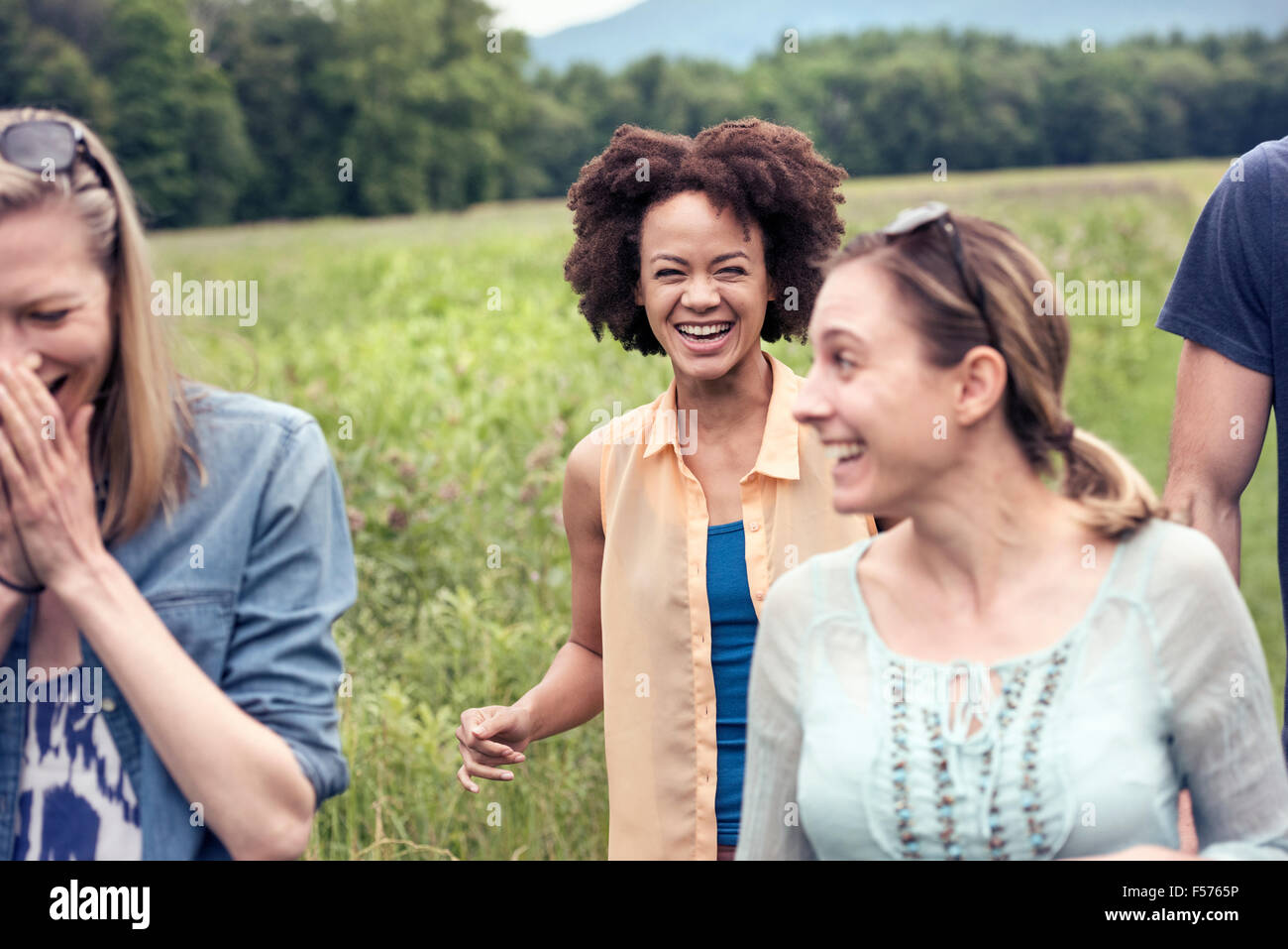 Eine Gruppe von Frauen gehen durch eine Wiese in der Landschaft, lachend. Stockfoto