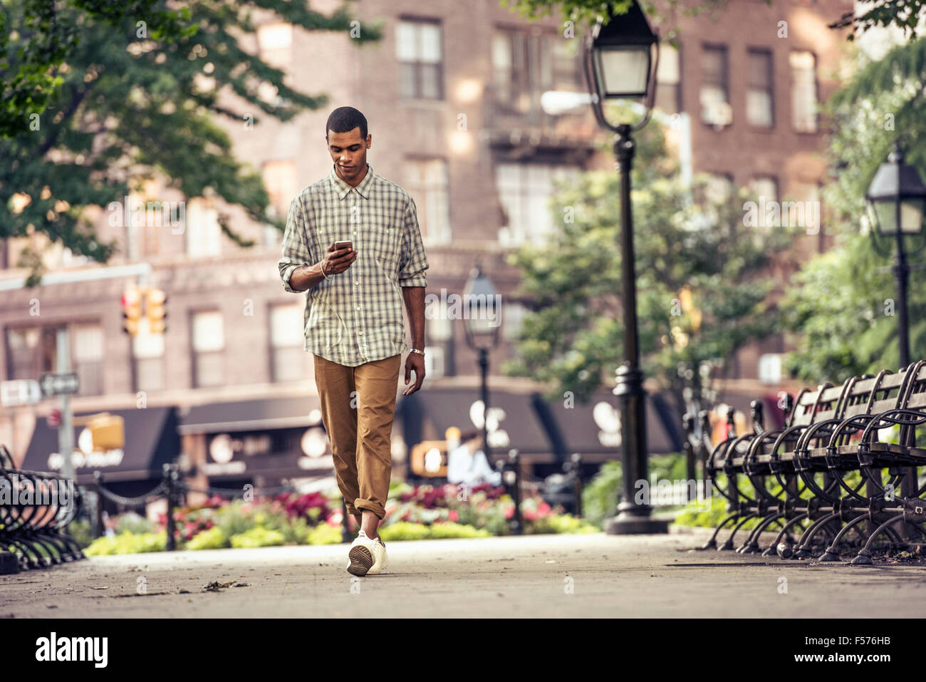 Ein Mann geht durch einen Blick auf sein Smartphone Marktplatz Stockfoto