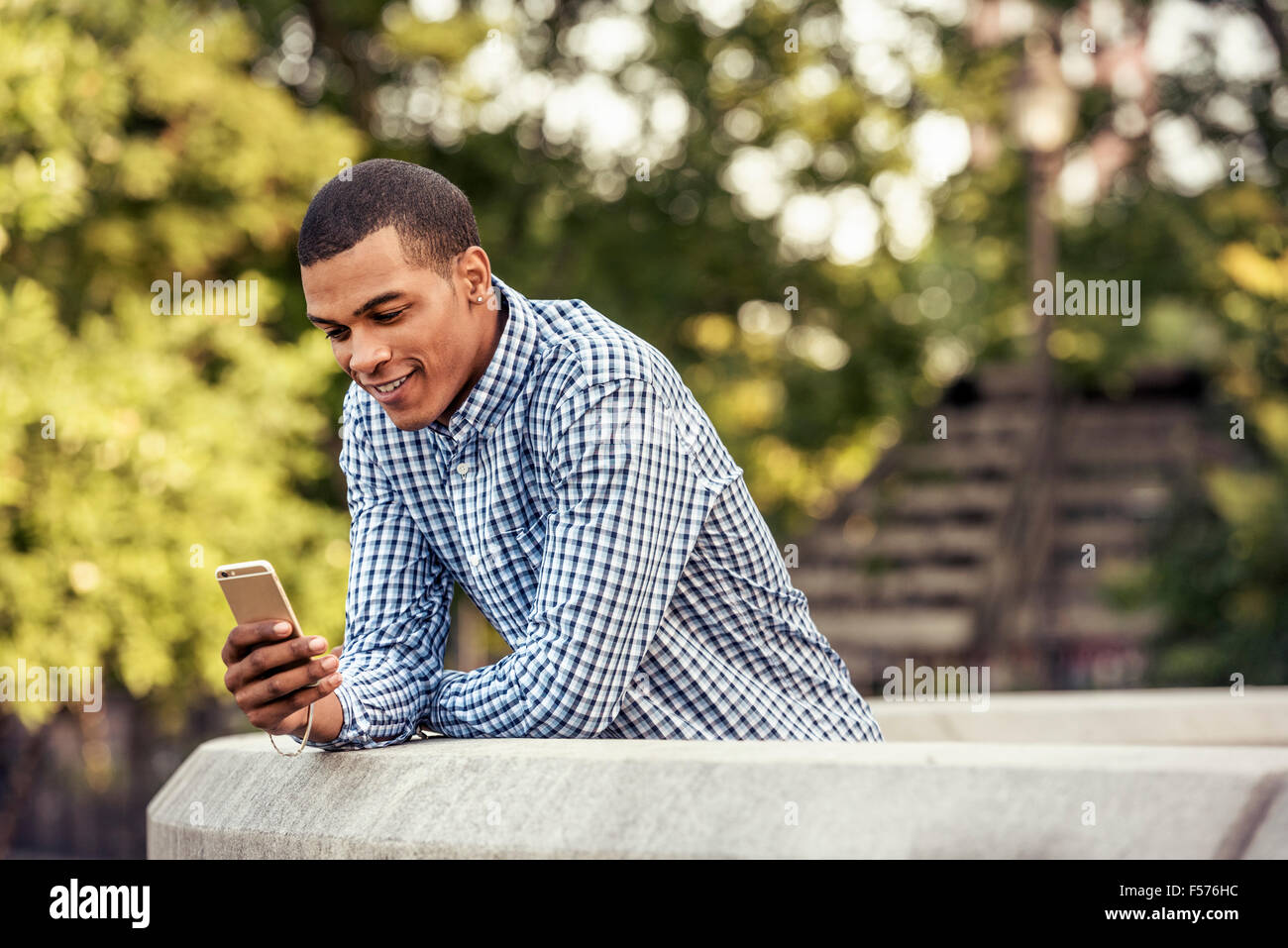 Ein Mann stützte sich auf eine Brüstung Blick auf ein smart phone Stockfoto