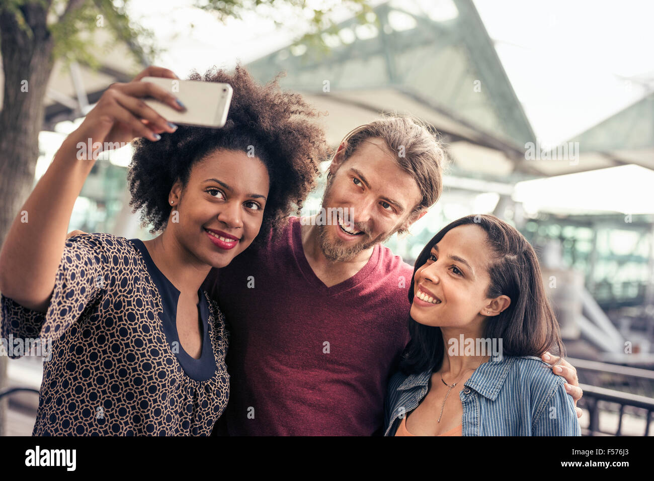 Drei Menschen, ein Mann und zwei Frauen, die Selfies im park Stockfoto
