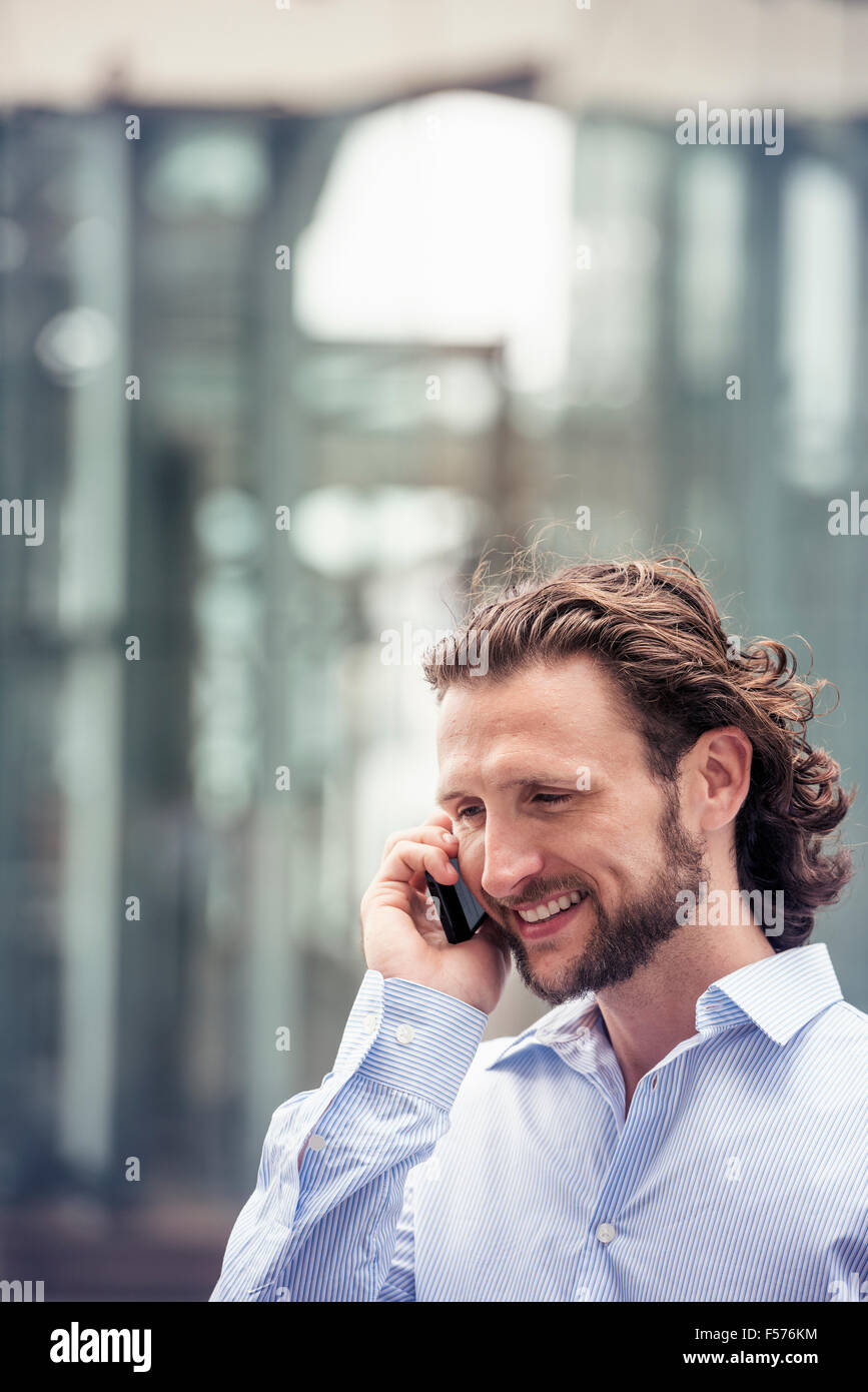 Ein Mann mit einem Bart reden über ein Handy in einer Straße in der Stadt. Stockfoto