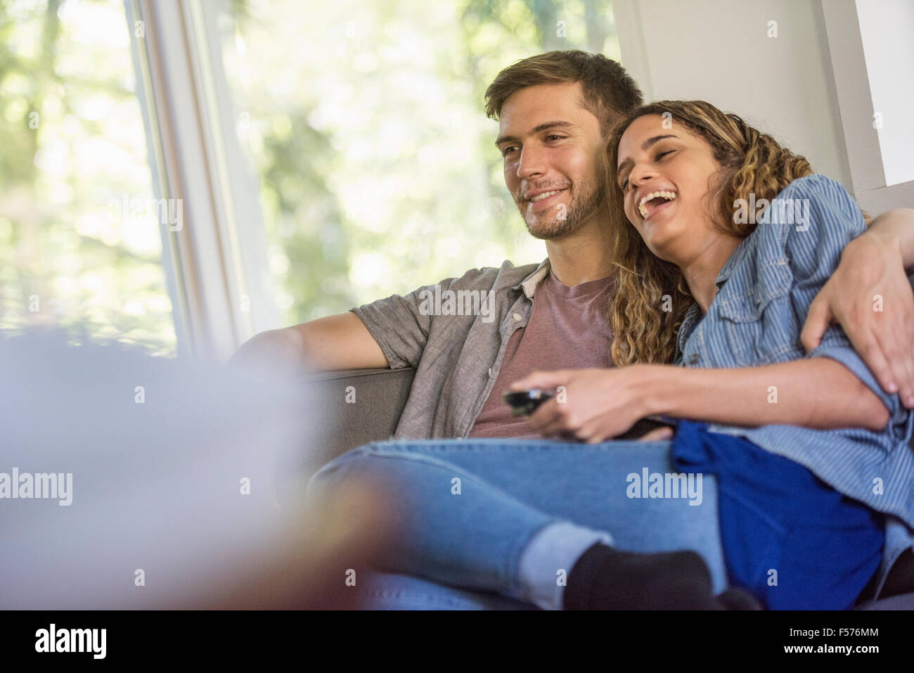 Ein paar, ein Mann und eine Frau sitzen nebeneinander lachen, auf einem Bildschirm. Stockfoto