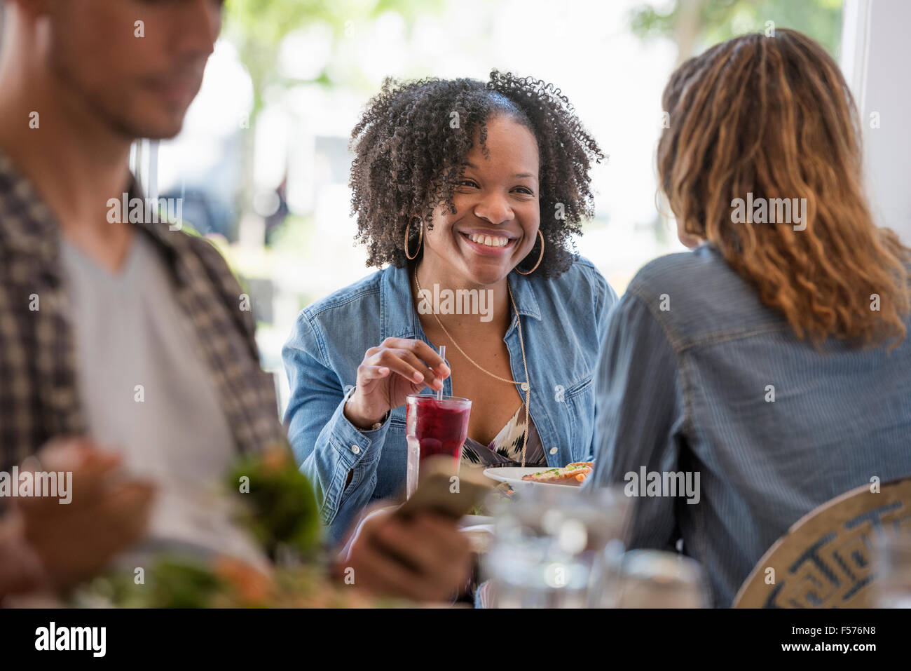 Drei Personen an den Tischen in einem Café. Zwei Frauen lachen. Stockfoto