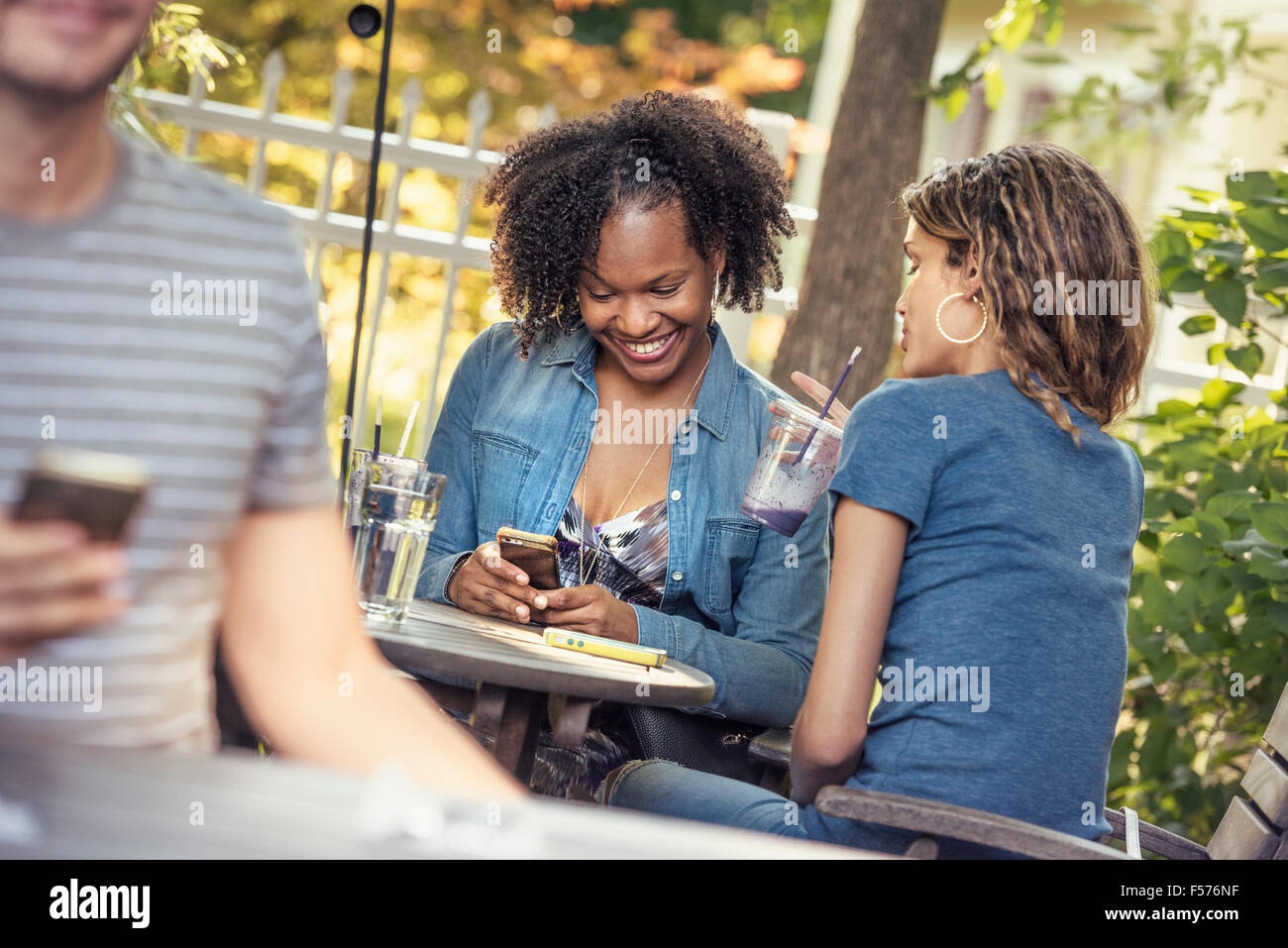 Drei Personen in einem Café Diner, zwei Überprüfung ihres Smartphones Stockfoto