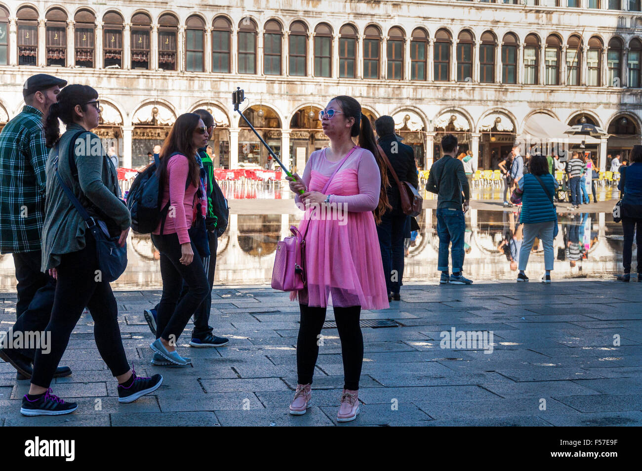 Frau in rosa Kleid Outfit nimmt ein Selbstporträt in Saint Markusplatz, Venedig, Italien Stockfoto