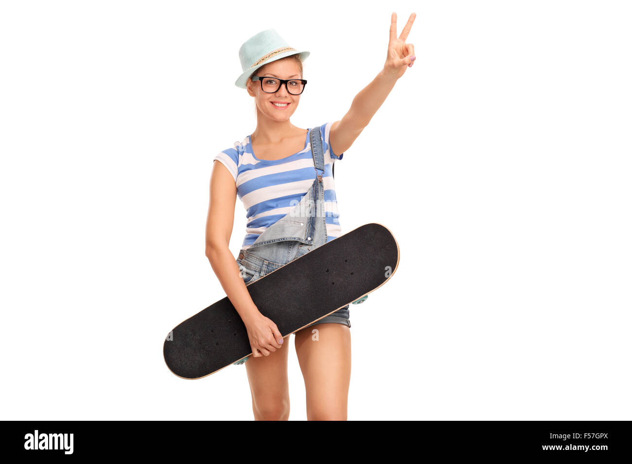 Studioaufnahme von jungen weiblichen Skater hält eine Skateboard und machen Frieden Handgeste isoliert auf weißem Hintergrund Stockfoto