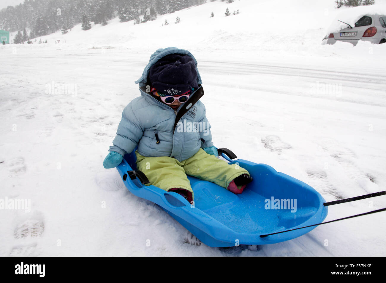 Kleines Baby auf einem Schlitten im Schnee. Stockfoto