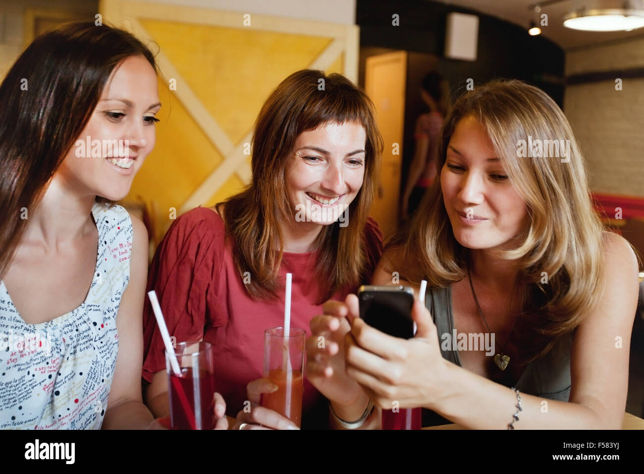 Freunde sprechen im Café und betrachten der Fotos auf Smartphone Stockfoto