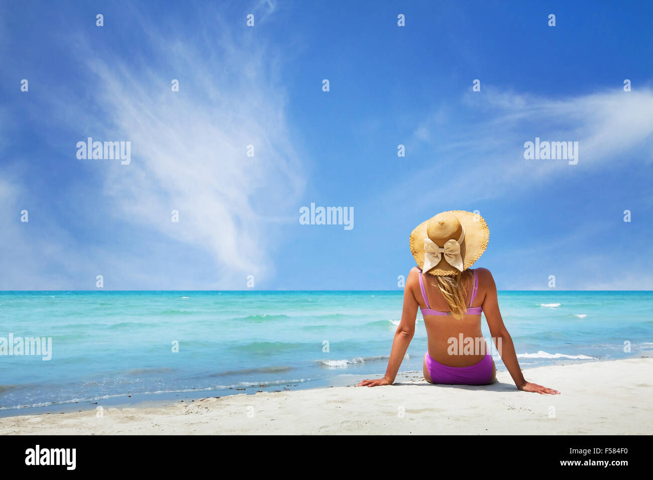 Frau sitzt am Paradiesstrand Stockfoto