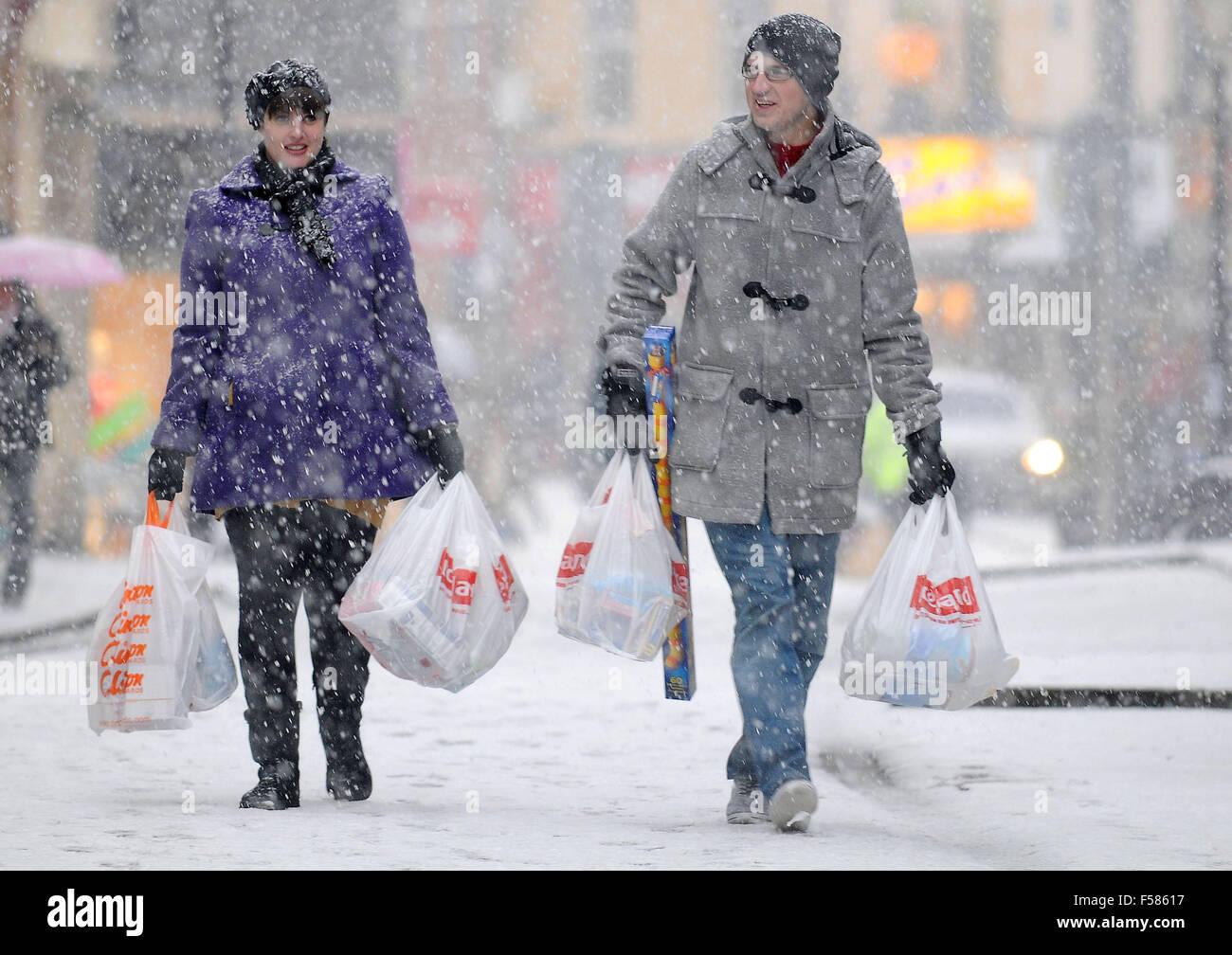 Käufer tragen Einkaufen in starkem Schneefall in Pontypridd, South Wales. Stockfoto