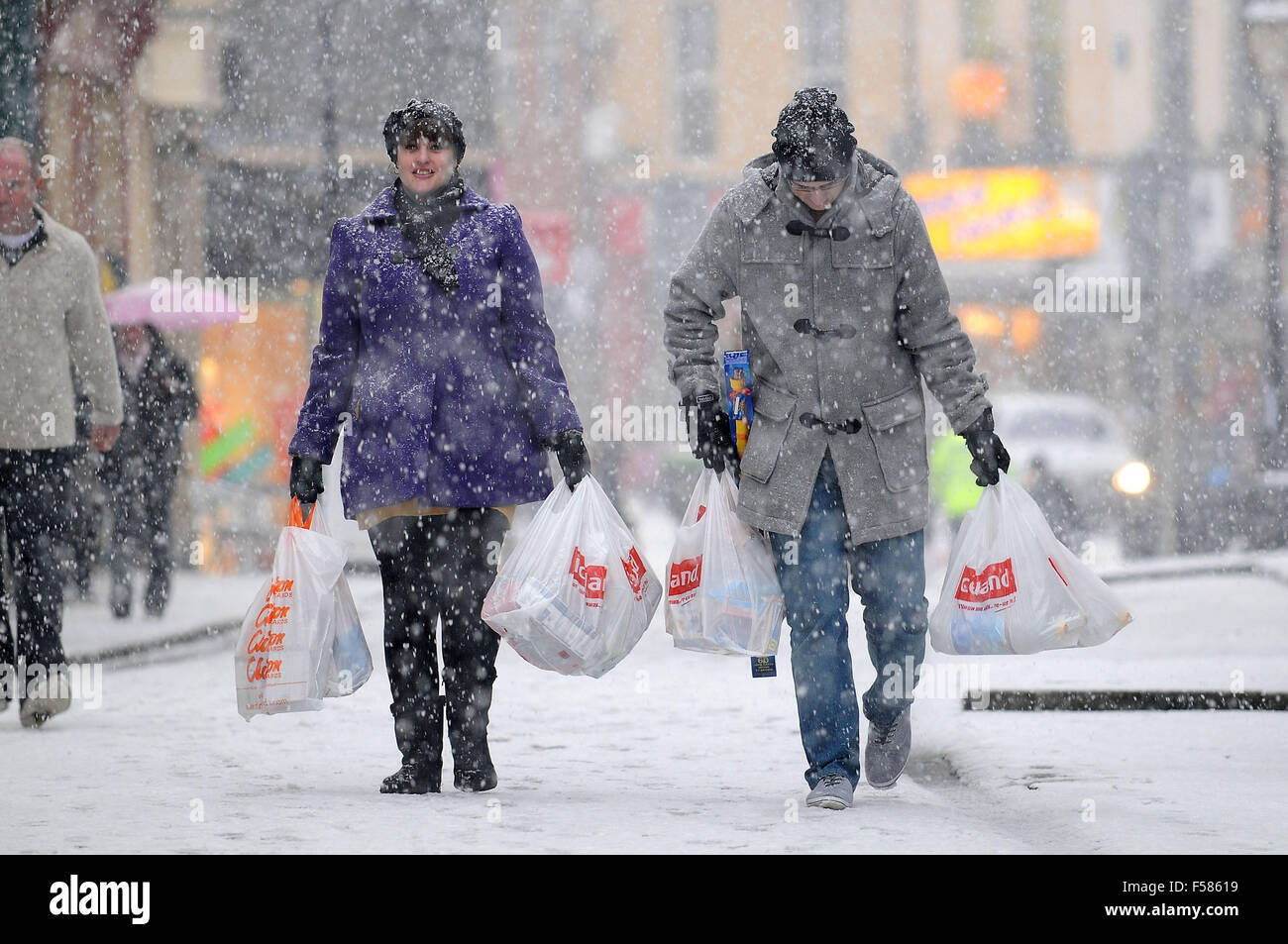 Käufer tragen Einkaufen in starkem Schneefall in Pontypridd, South Wales. Stockfoto