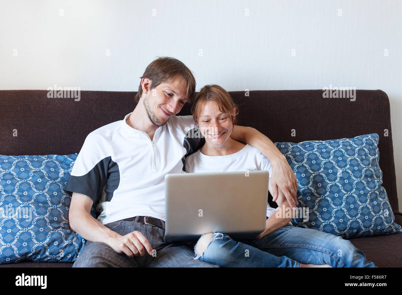 glücklich lächelnde paar mit Laptop zu Hause, Online-shopping Stockfoto
